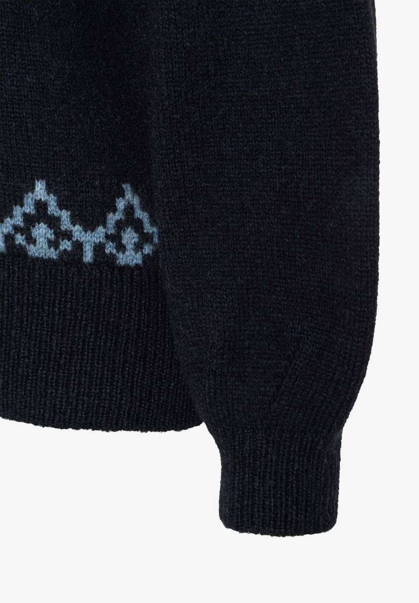 MORE & MORE Oberteil: Nahaufnahme eines dunkelblauen Pullovers mit Rippenbündchen am Ärmel und einem Muster MORE & MORE Oberteil: Nahaufnahme eines dunkelblauen Pullovers mit Rippenbündchen am Ärmel und einem Muster