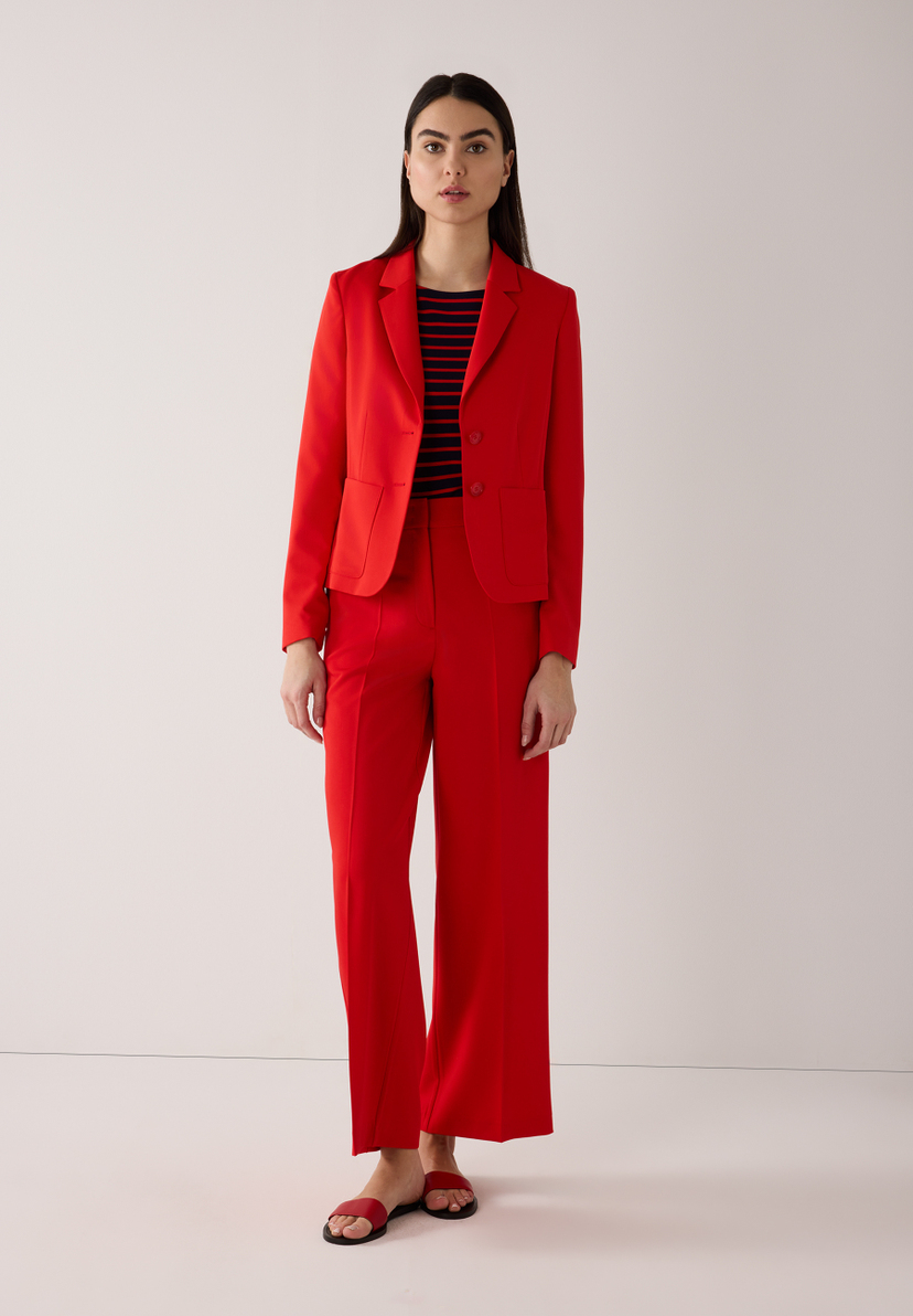 Eine Frau in einem roten MORE & MORE Blazer und einer passenden Hose, dazu ein gestreiftes Oberteil. Eine Frau in einem roten MORE & MORE Blazer und einer passenden Hose, dazu ein gestreiftes Oberteil.