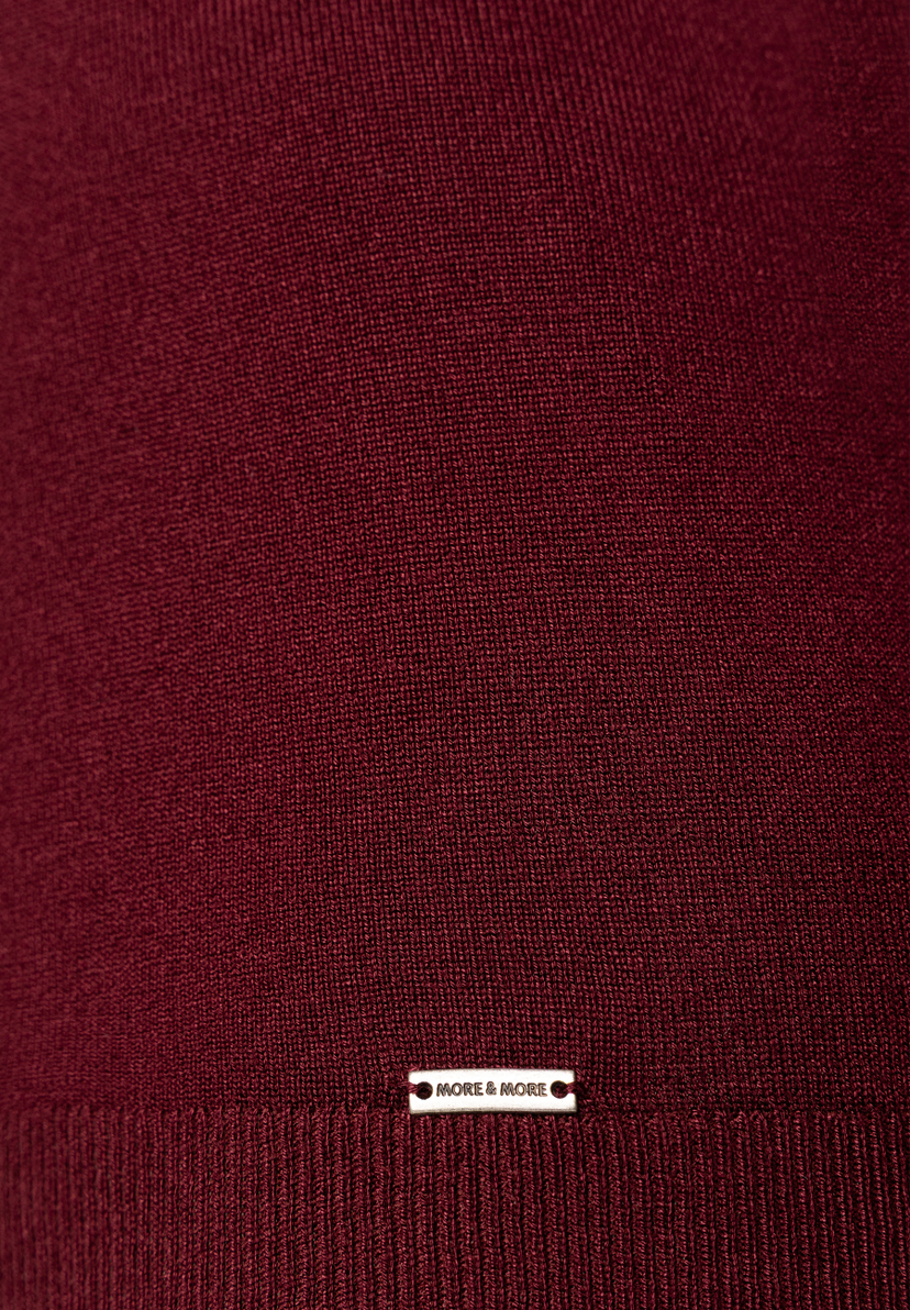 MORE & MORE dunkelroter Feinstrickpullover, Nahaufnahme des Saums mit Logoplakette. Strukturierter Strickstoff. MORE & MORE dunkelroter Feinstrickpullover, Nahaufnahme des Saums mit Logoplakette. Strukturierter Strickstoff.