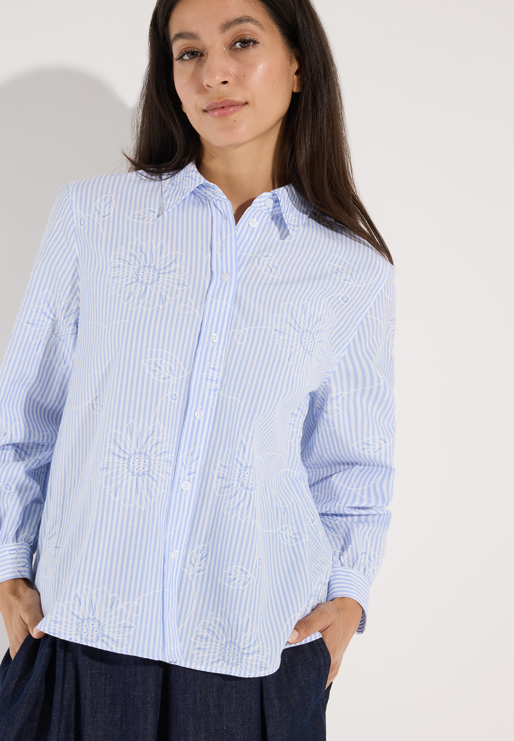 MORE & MORE Bluse: Eine Frau trägt eine hellblaue Baumwollmischungs-Popeline-Bluse mit weißen Streifen und gestickten Blumen.