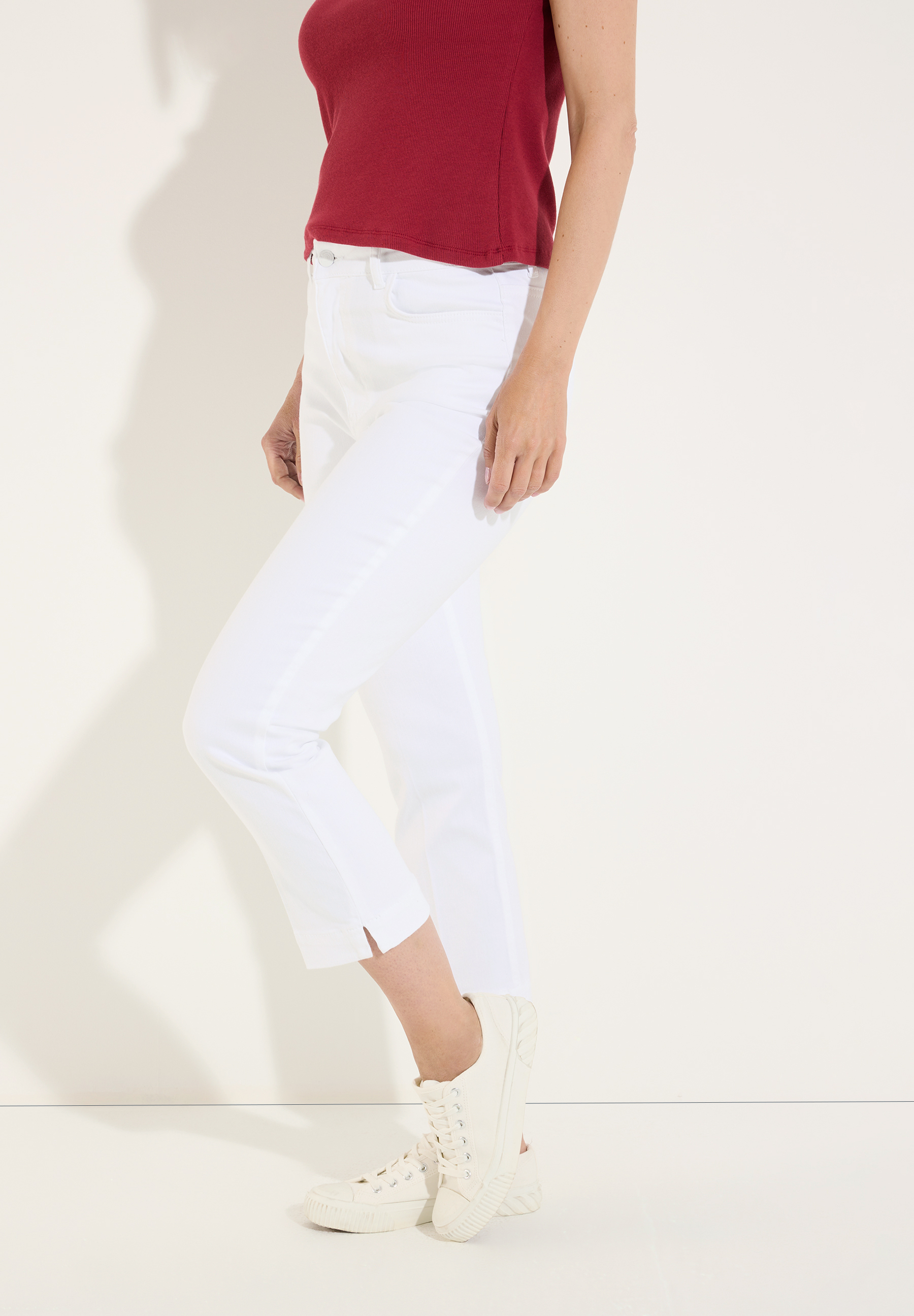 MORE & MORE Jeans: Weiße Denim-Jeans mit hohem Bund und seitlichen Schlitzen am Knöchel. Hinten eine gemusterte Bluse. MORE & MORE Jeans: Weiße Denim-Jeans mit hohem Bund und seitlichen Schlitzen am Knöchel. Hinten eine gemusterte Bluse.