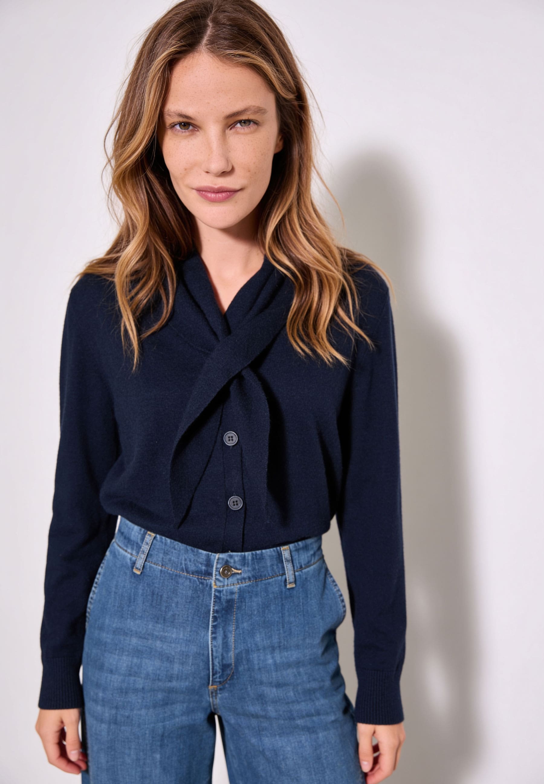 AI generated - MORE & MORE Pullover: Eine Frau trägt einen marineblauen Pullover mit Schleife und eine Jeans.