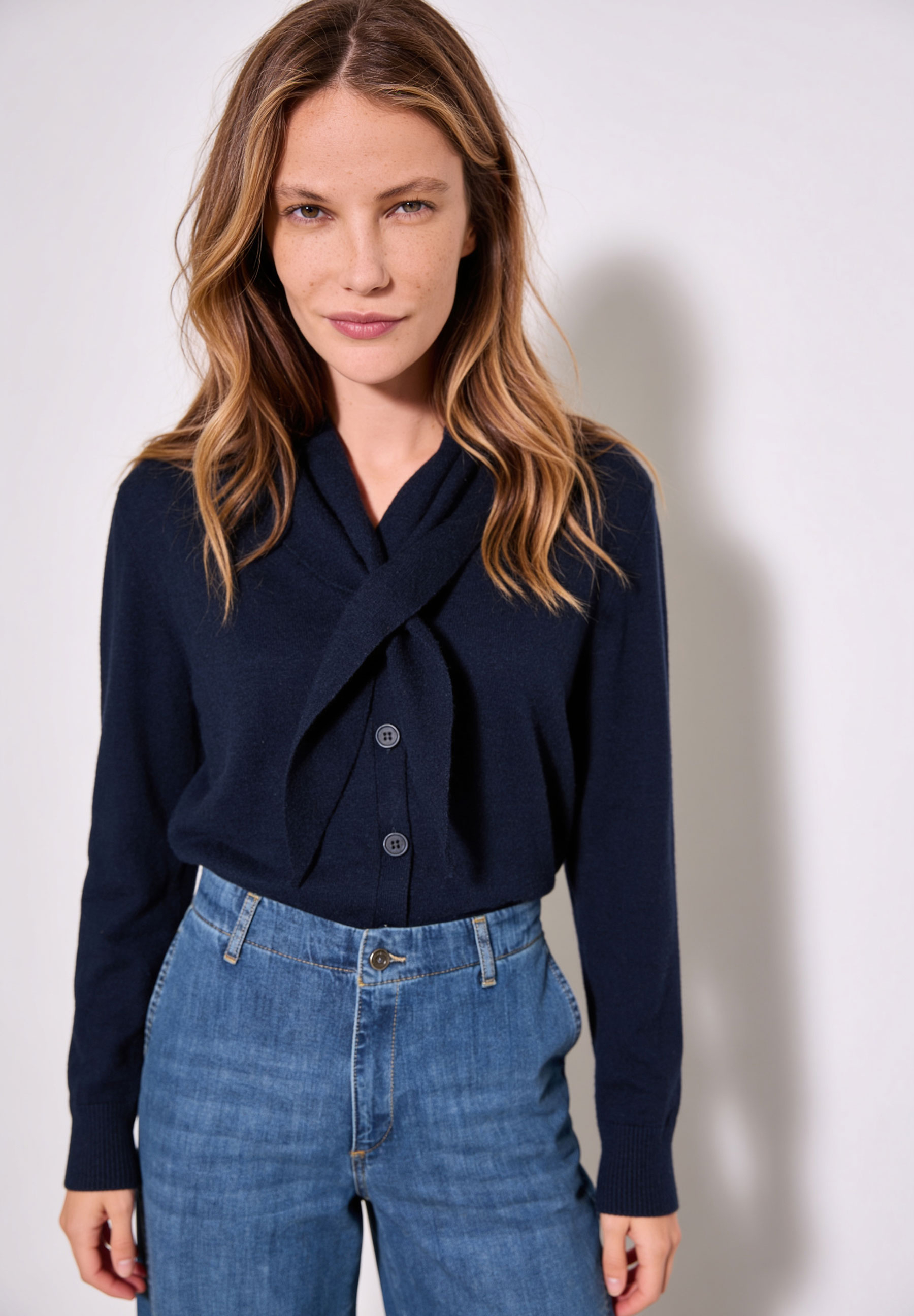 AI generated - MORE & MORE Pullover: Eine Frau trägt einen marineblauen Pullover mit Schleife und eine Jeans.