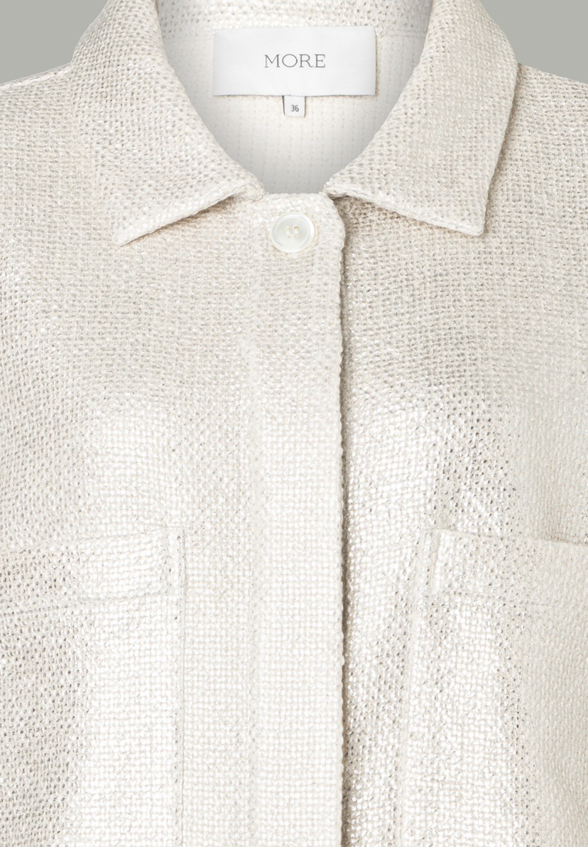 Nahaufnahme eines MORE & MORE Oberteils mit Kragen, Knopf und Brusttasche. Nahaufnahme eines MORE & MORE Oberteils mit Kragen, Knopf und Brusttasche.