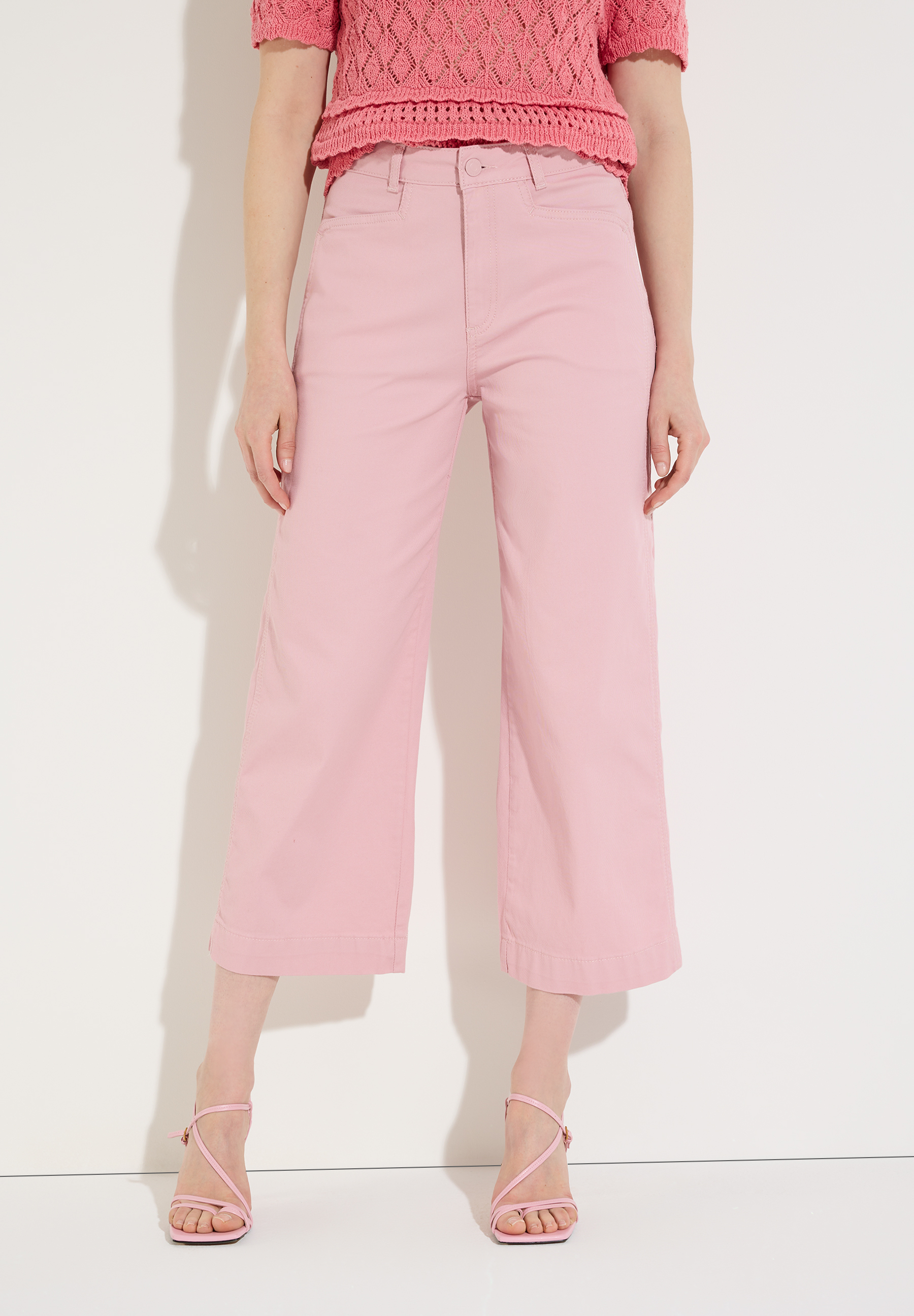 Eine Person mit MORE & MORE Hose und passenden Schuhen steht vor einer Wand.