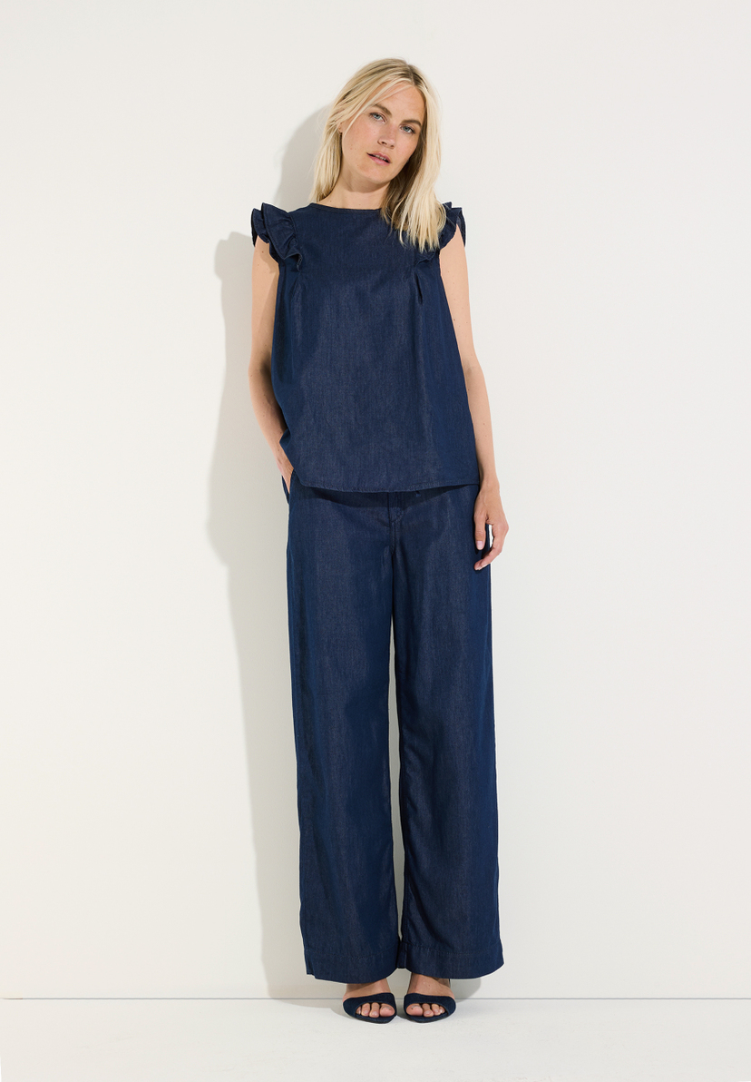 MORE & MORE Damen-Oberteil aus softem Denim mit Rüschen und passender weiter Hose in Dunkelblau, Model posiert. MORE & MORE Damen-Oberteil aus softem Denim mit Rüschen und passender weiter Hose in Dunkelblau, Model posiert.