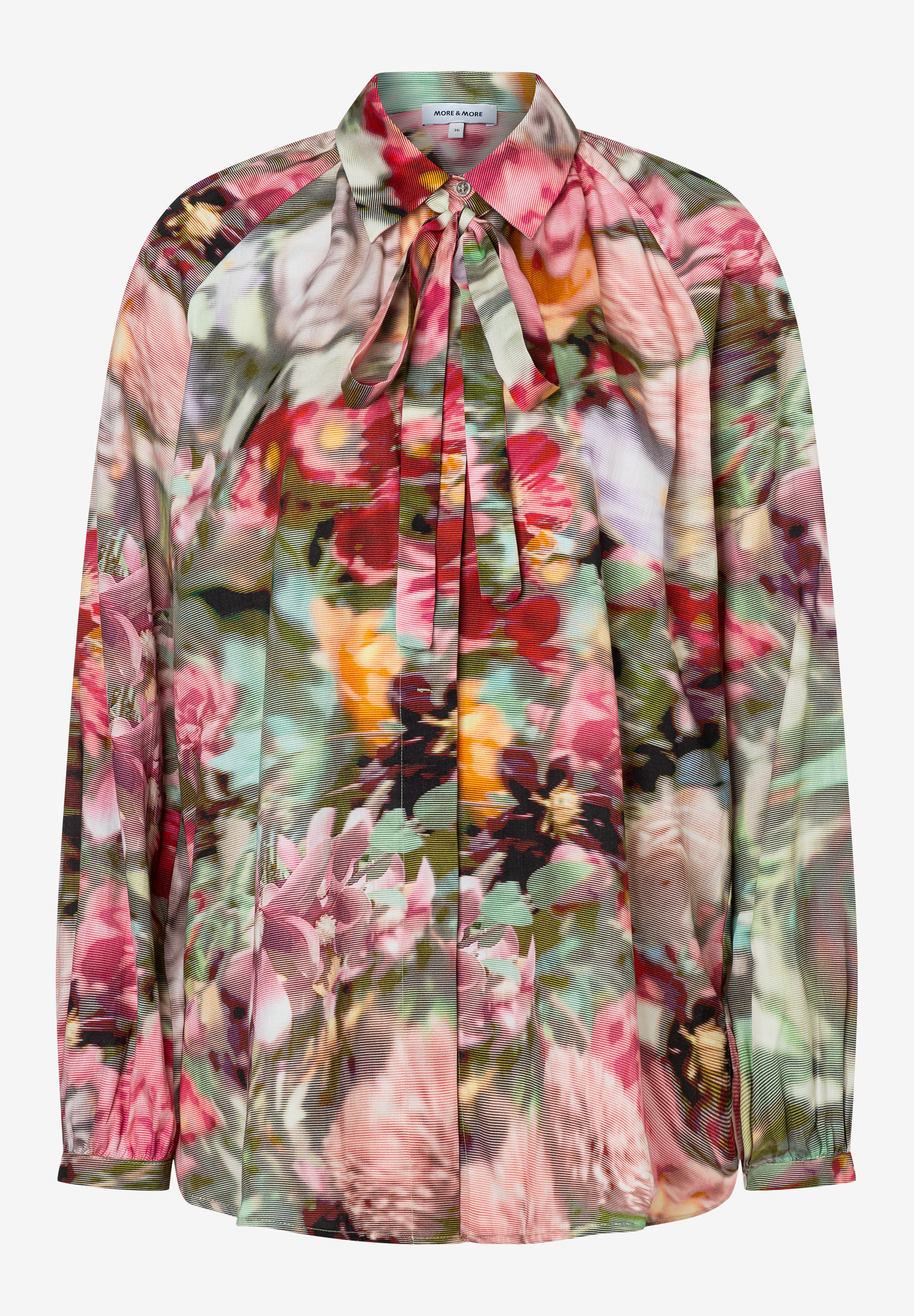 Eine MORE & MORE Bluse mit Blumenmuster und langen Ärmeln, die mit einer Schleife am Kragen geschlossen wird. Eine MORE & MORE Bluse mit Blumenmuster und langen Ärmeln, die mit einer Schleife am Kragen geschlossen wird.