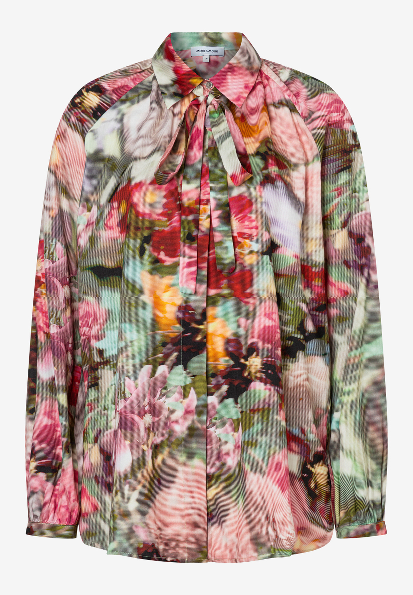 Eine MORE & MORE Bluse mit Blumenmuster und langen Ärmeln, die mit einer Schleife am Kragen geschlossen wird. Eine MORE & MORE Bluse mit Blumenmuster und langen Ärmeln, die mit einer Schleife am Kragen geschlossen wird.