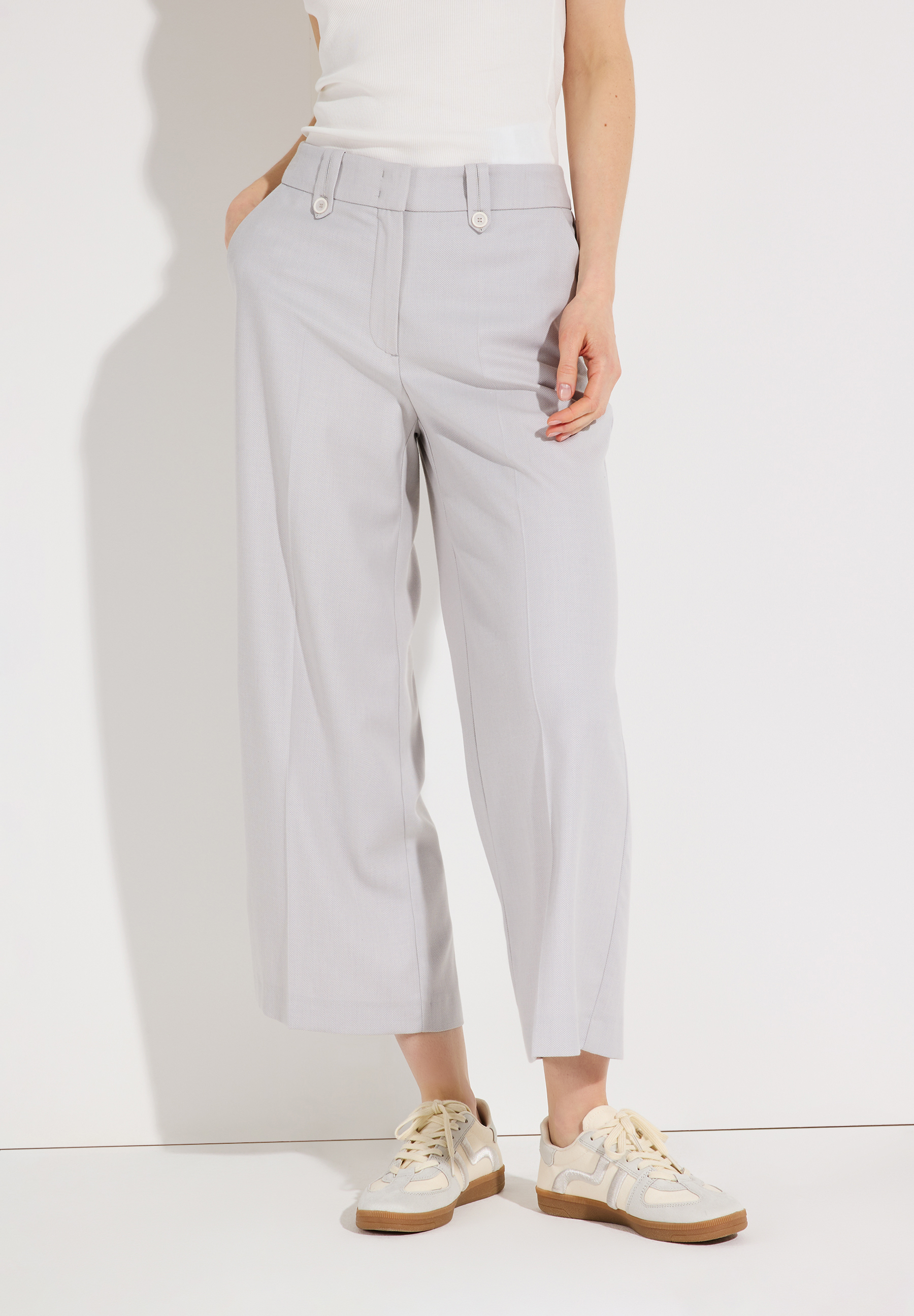 Eine Person trägt eine graue MORE & MORE Hose mit angenehmem Tragekomfort und dazu passende Turnschuhe.