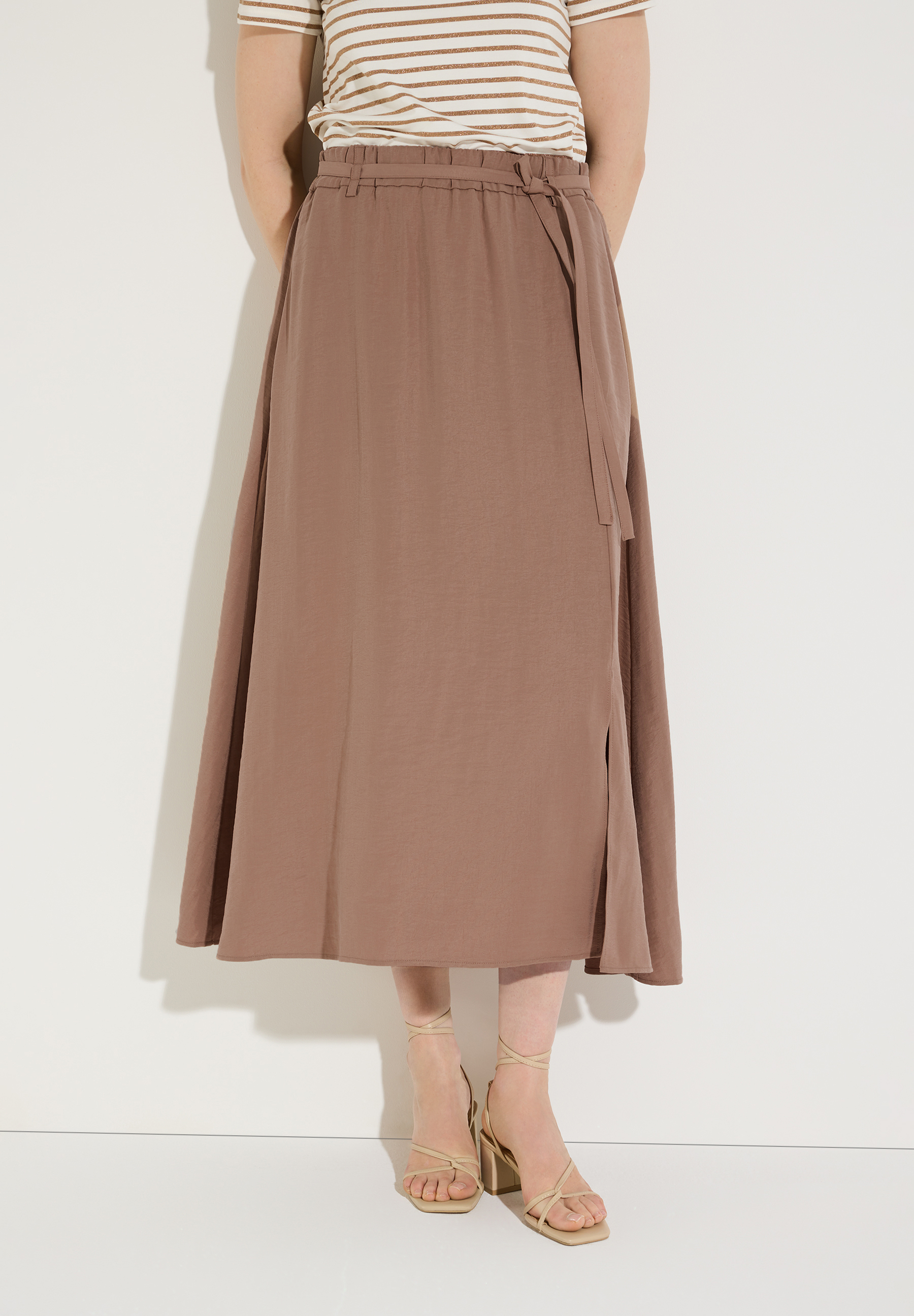 Eine Person mit MORE & MORE Rock mit fließendem Webware-Stoff und Sandalen. Eine Person mit MORE & MORE Rock mit fließendem Webware-Stoff und Sandalen.