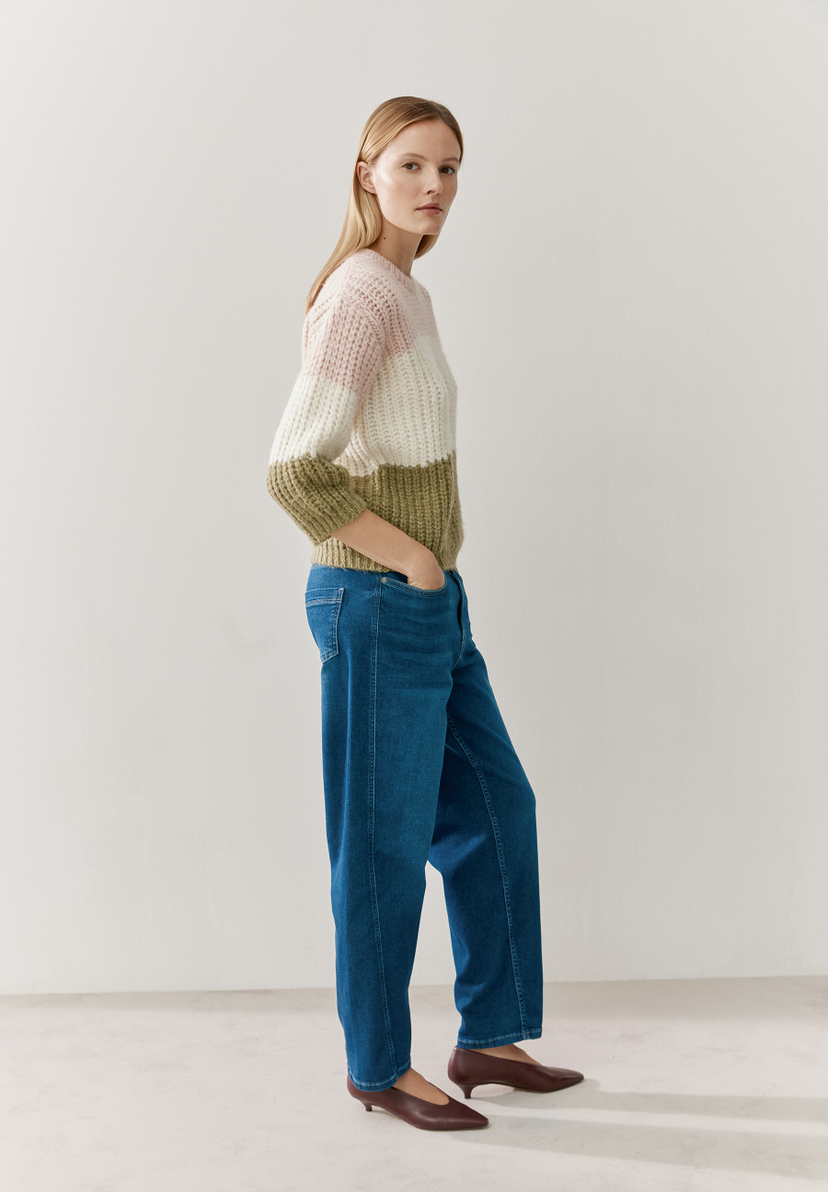 Eine Frau in Jeans und MORE & MORE Rippstrick-Pullover mit Farbblöcken in Rosa, Weiß und Olivgrün. Eine Frau in Jeans und MORE & MORE Rippstrick-Pullover mit Farbblöcken in Rosa, Weiß und Olivgrün.