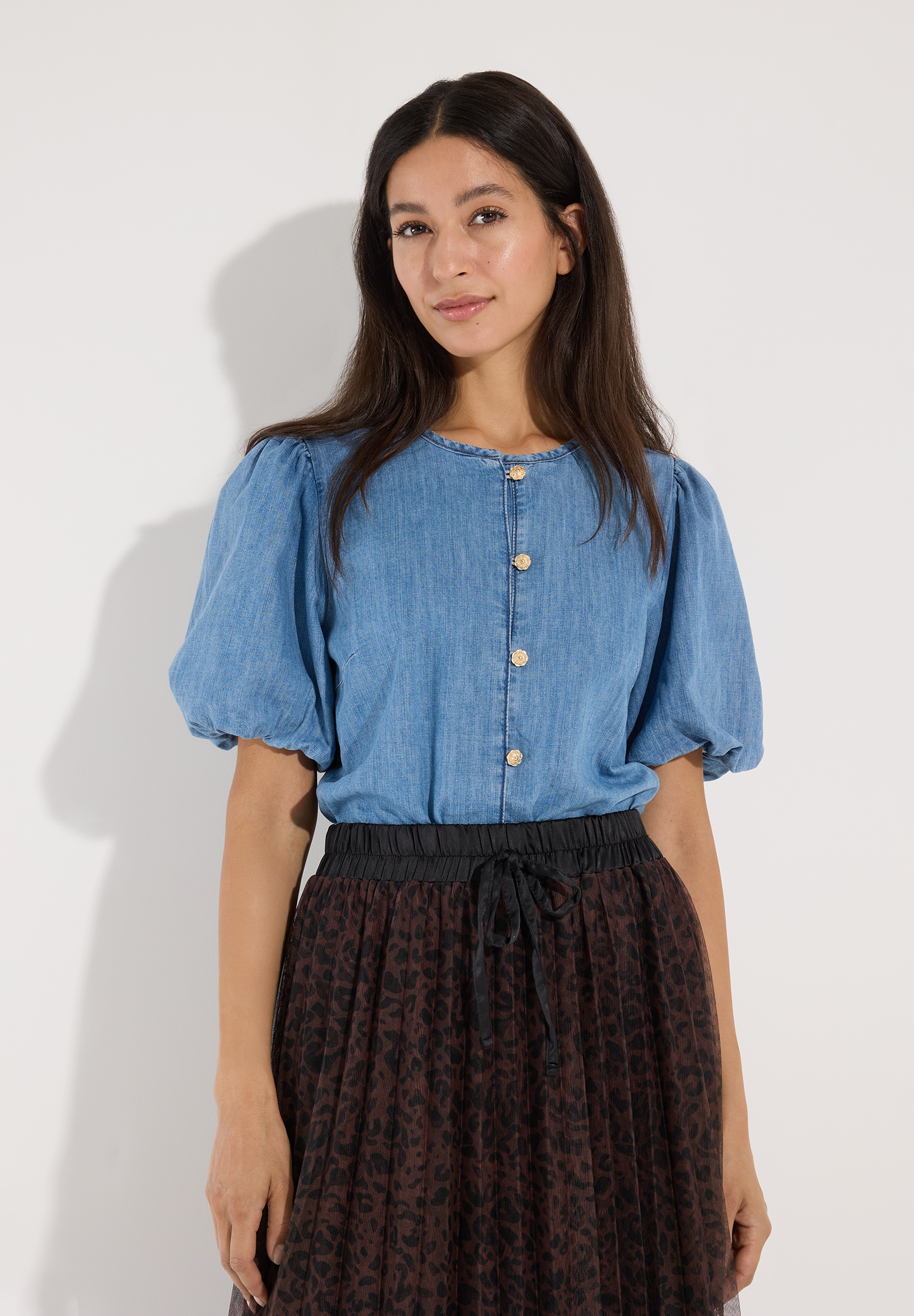 MORE & MORE Bluse aus Baumwolldenim in Hellblau mit goldenen Knöpfen und Puffärmeln, kombiniert mit einem Rock mit Leopardenmuster.