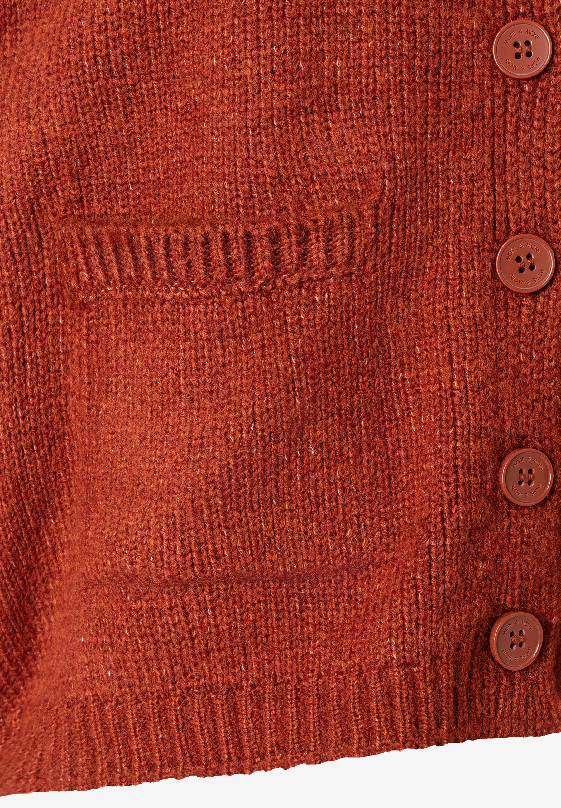 Detailaufnahme eines MORE & MORE Strick-Oberteils in Rotbraun mit Knopfleiste und aufgesetzter Tasche. Detailaufnahme eines MORE & MORE Strick-Oberteils in Rotbraun mit Knopfleiste und aufgesetzter Tasche.