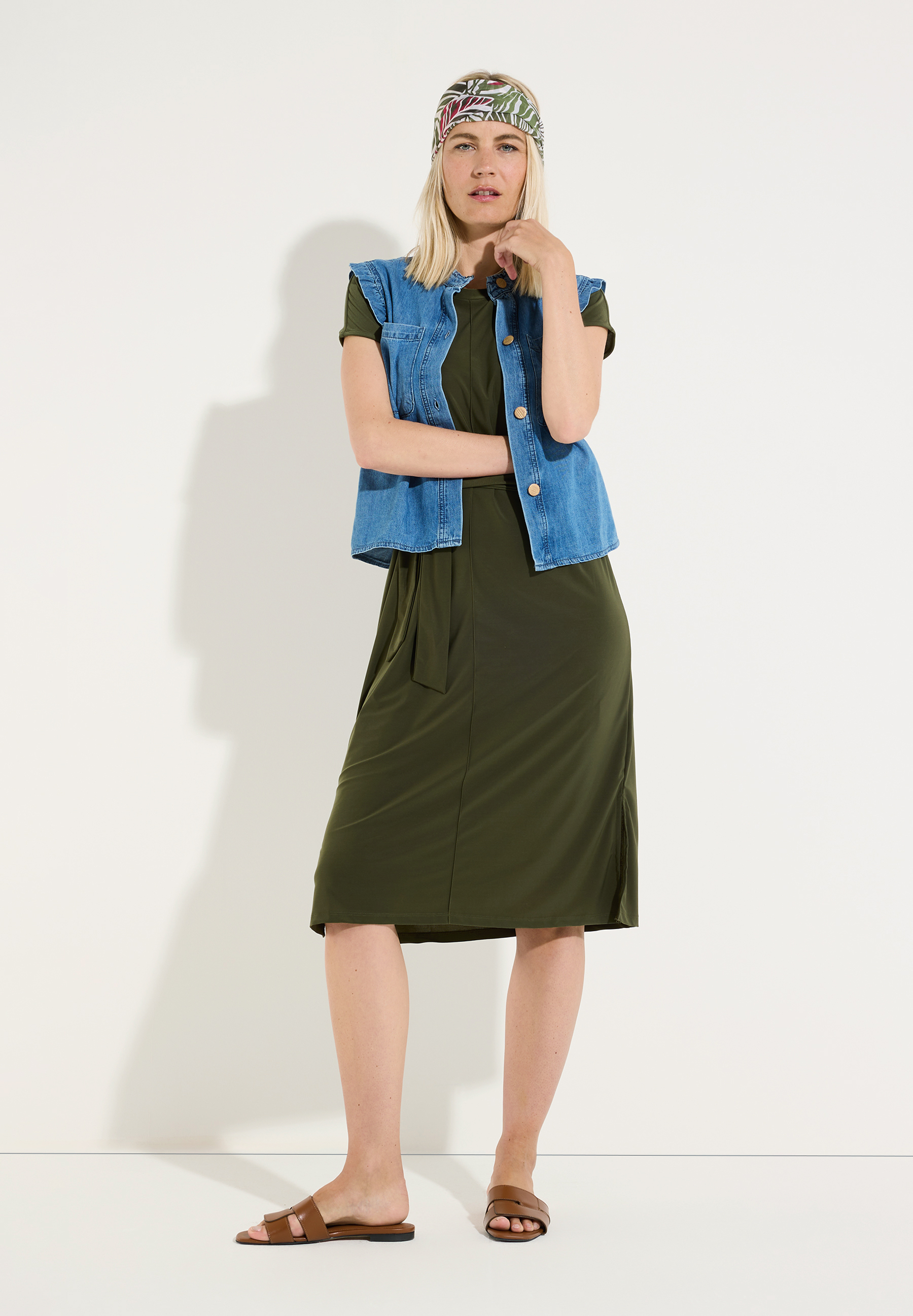 MORE & MORE Midikleid in Dunkelgrün mit bindeband und kurzem Arm. Eine blonde Frau trägt dazu eine Jeansweste und braune Sandalen. MORE & MORE Midikleid in Dunkelgrün mit bindeband und kurzem Arm. Eine blonde Frau trägt dazu eine Jeansweste und braune Sandalen.