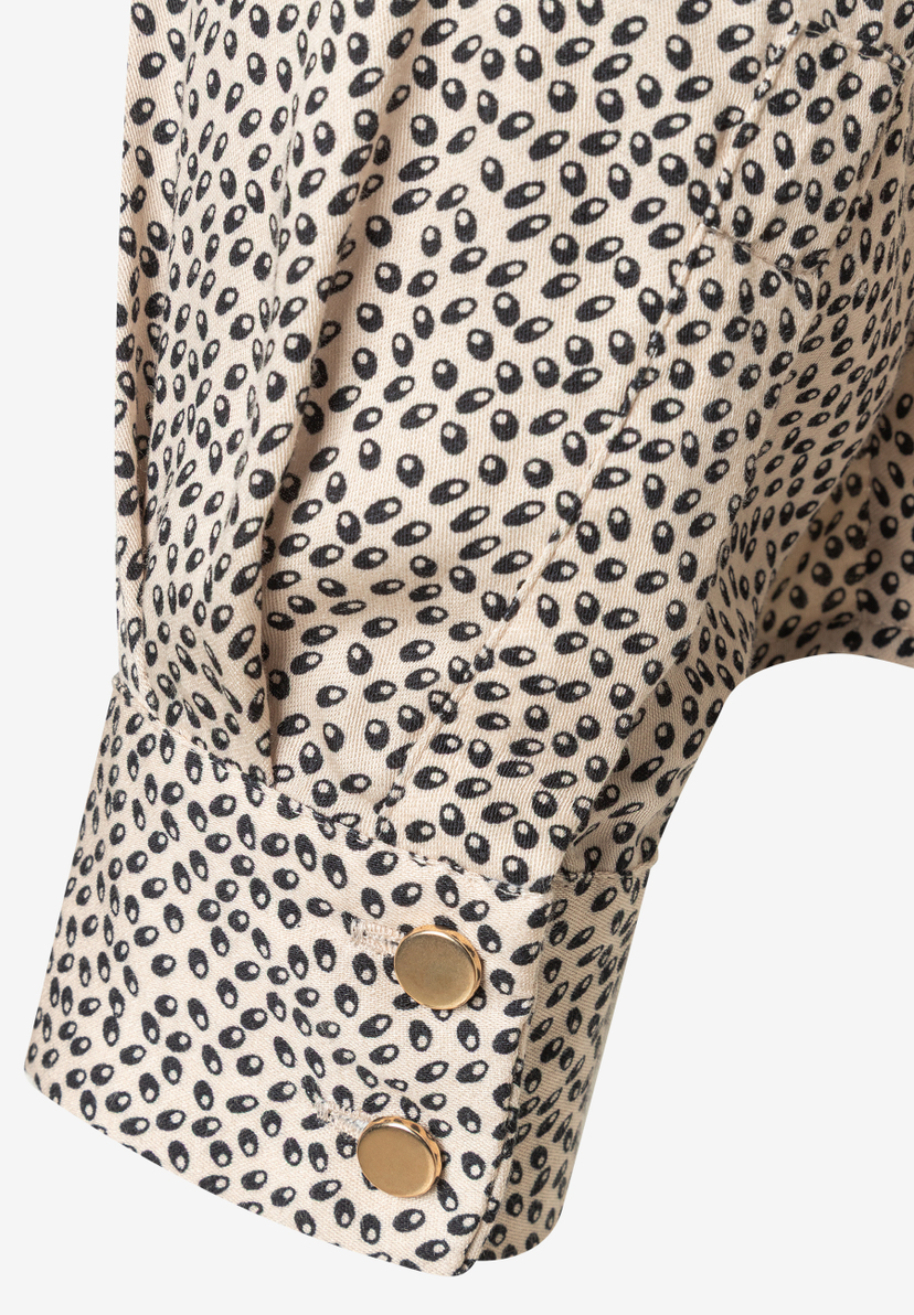 MORE & MORE Bluse: Detailaufnahme des Blusenärmels mit beigem Stoff und schwarzem, unregelmäßigem Punktmuster, goldene Knöpfe am Ärmelsaum.