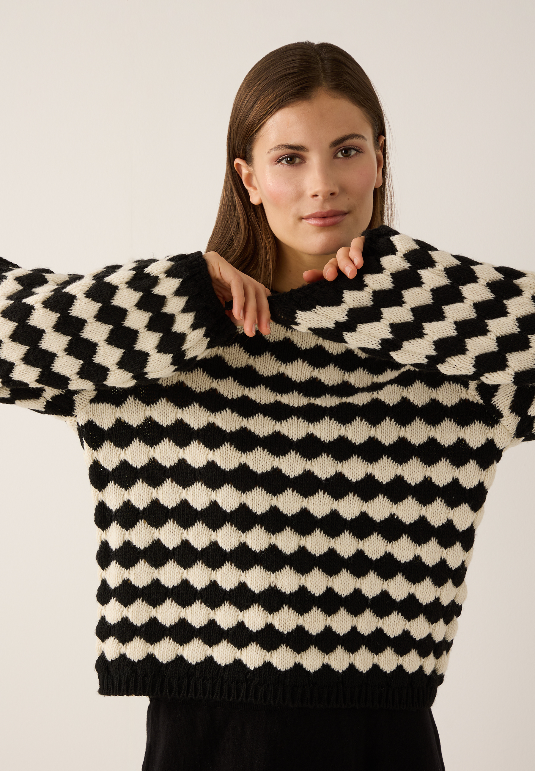 Eine Frau mit MORE & MORE Strickpullover in Schwarz-Weiß-Muster, angenehmer Tragekomfort.
