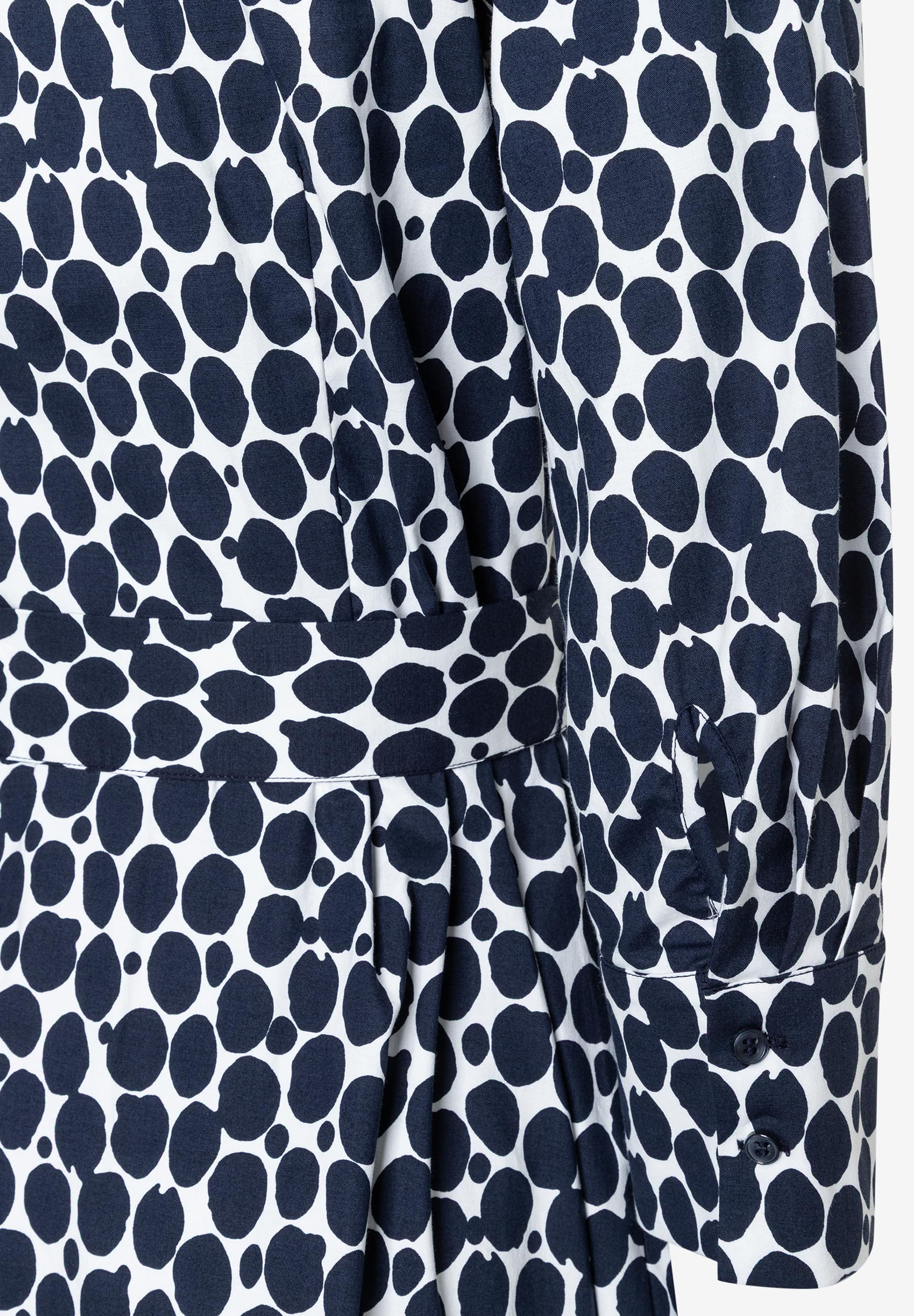 Detailaufnahme eines MORE & MORE Kleides mit blau-weißem Punktmuster und langen Ärmeln. Detailaufnahme eines MORE & MORE Kleides mit blau-weißem Punktmuster und langen Ärmeln.