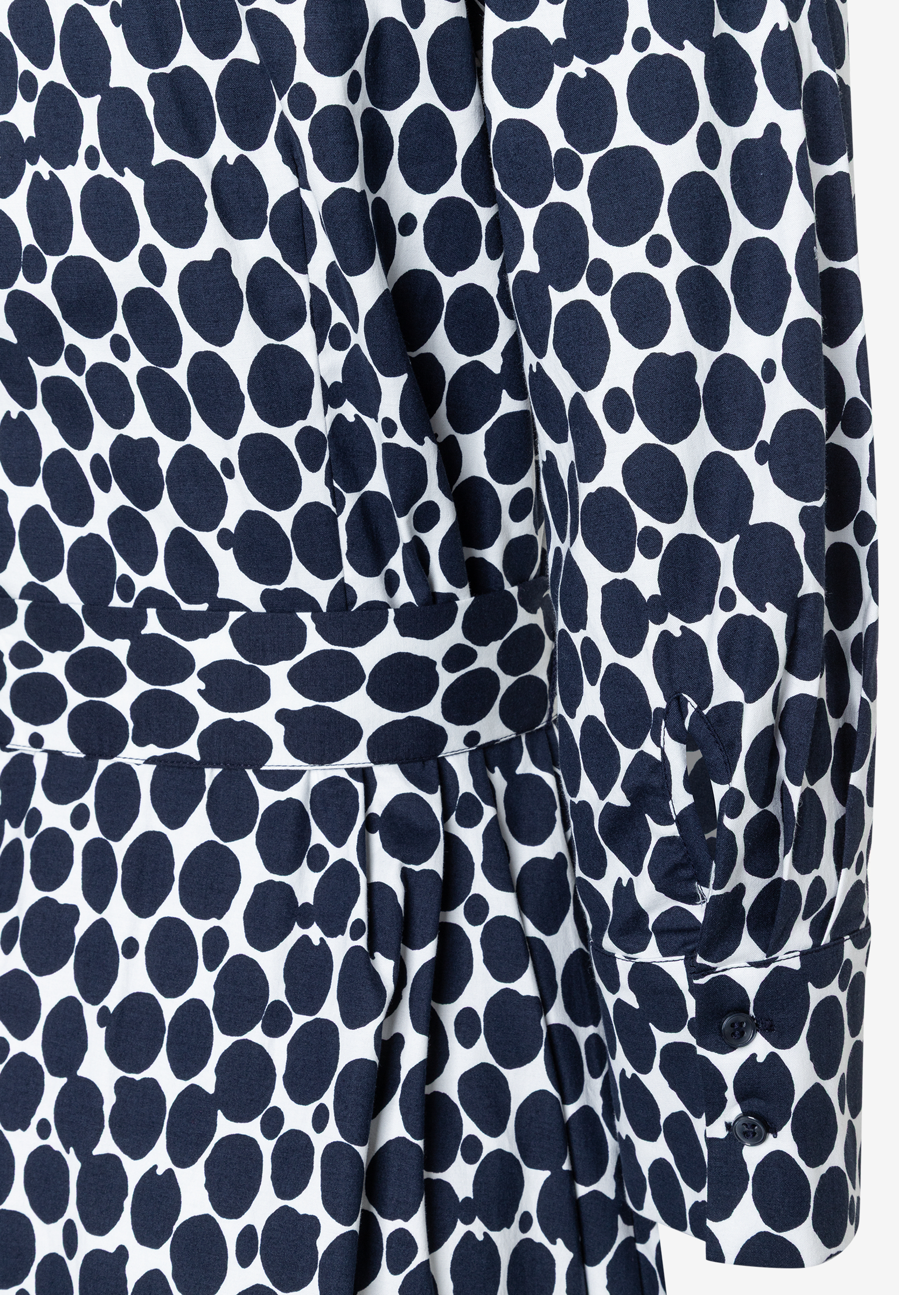 Detailaufnahme eines MORE & MORE Kleides mit blau-weißem Punktmuster und langen Ärmeln. Detailaufnahme eines MORE & MORE Kleides mit blau-weißem Punktmuster und langen Ärmeln.