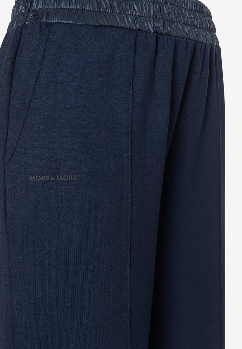 Nahaufnahme einer dunkelblauen MORE & MORE Hose mit glänzendem Bund. Nahaufnahme einer dunkelblauen MORE & MORE Hose mit glänzendem Bund.