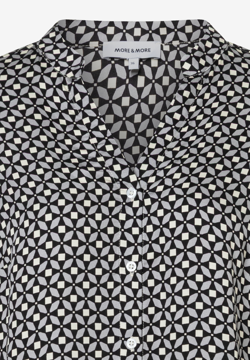 Nahaufnahme einer MORE & MORE Bluse mit geometrischem Muster und Knopfleiste. Nahaufnahme einer MORE & MORE Bluse mit geometrischem Muster und Knopfleiste.