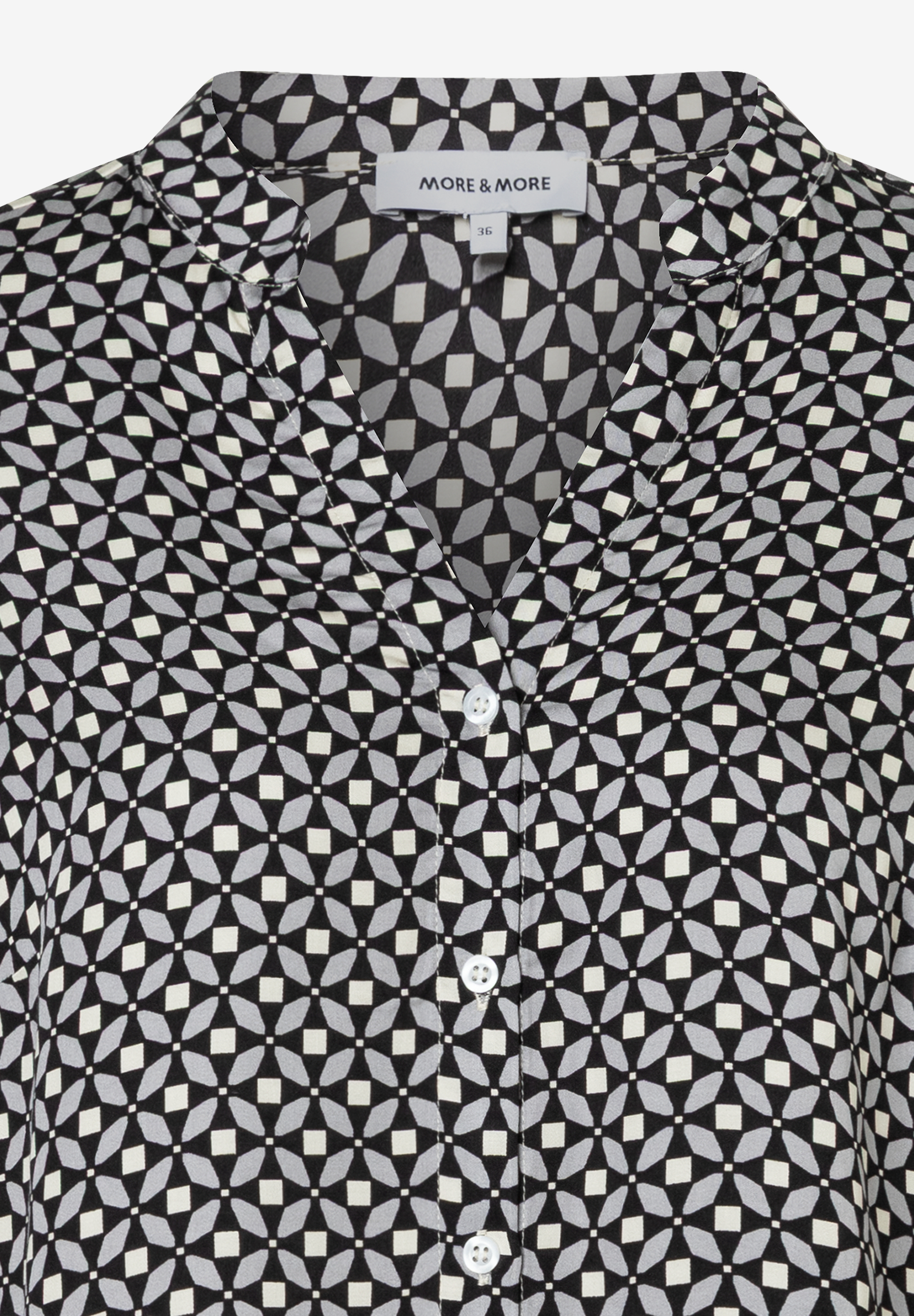 Nahaufnahme einer MORE & MORE Bluse mit geometrischem Muster und Knopfleiste. Nahaufnahme einer MORE & MORE Bluse mit geometrischem Muster und Knopfleiste.