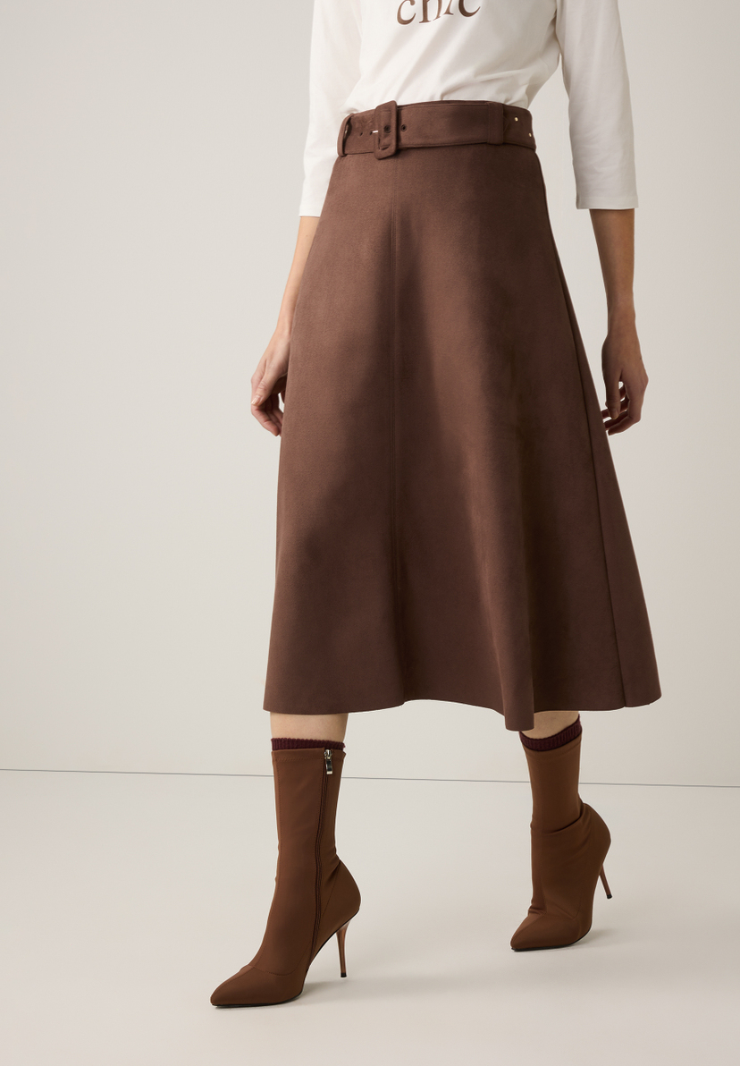 Ein Model trägt einen braunen MORE & MORE Rock mit Gürtel und passende Stiefel. Ein Model trägt einen braunen MORE & MORE Rock mit Gürtel und passende Stiefel.