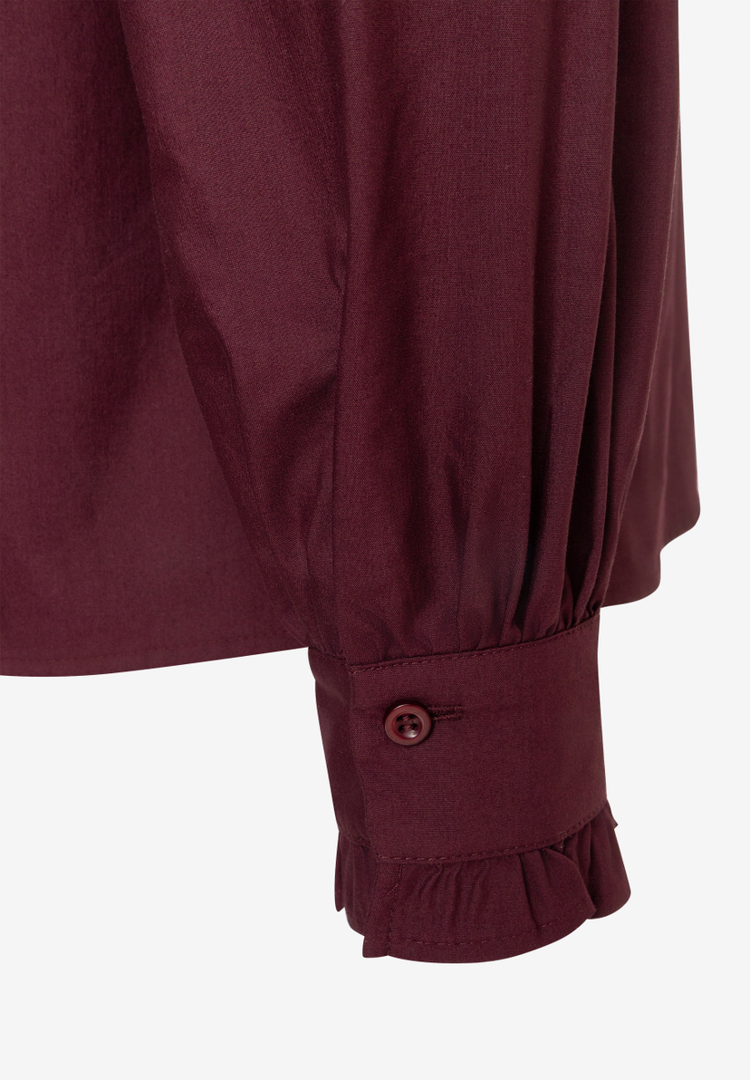 MORE & MORE Bluse: Detailansicht des weinroten Ärmels mit Manschette, Knopf und Rüsche am Saum. MORE & MORE Bluse: Detailansicht des weinroten Ärmels mit Manschette, Knopf und Rüsche am Saum.