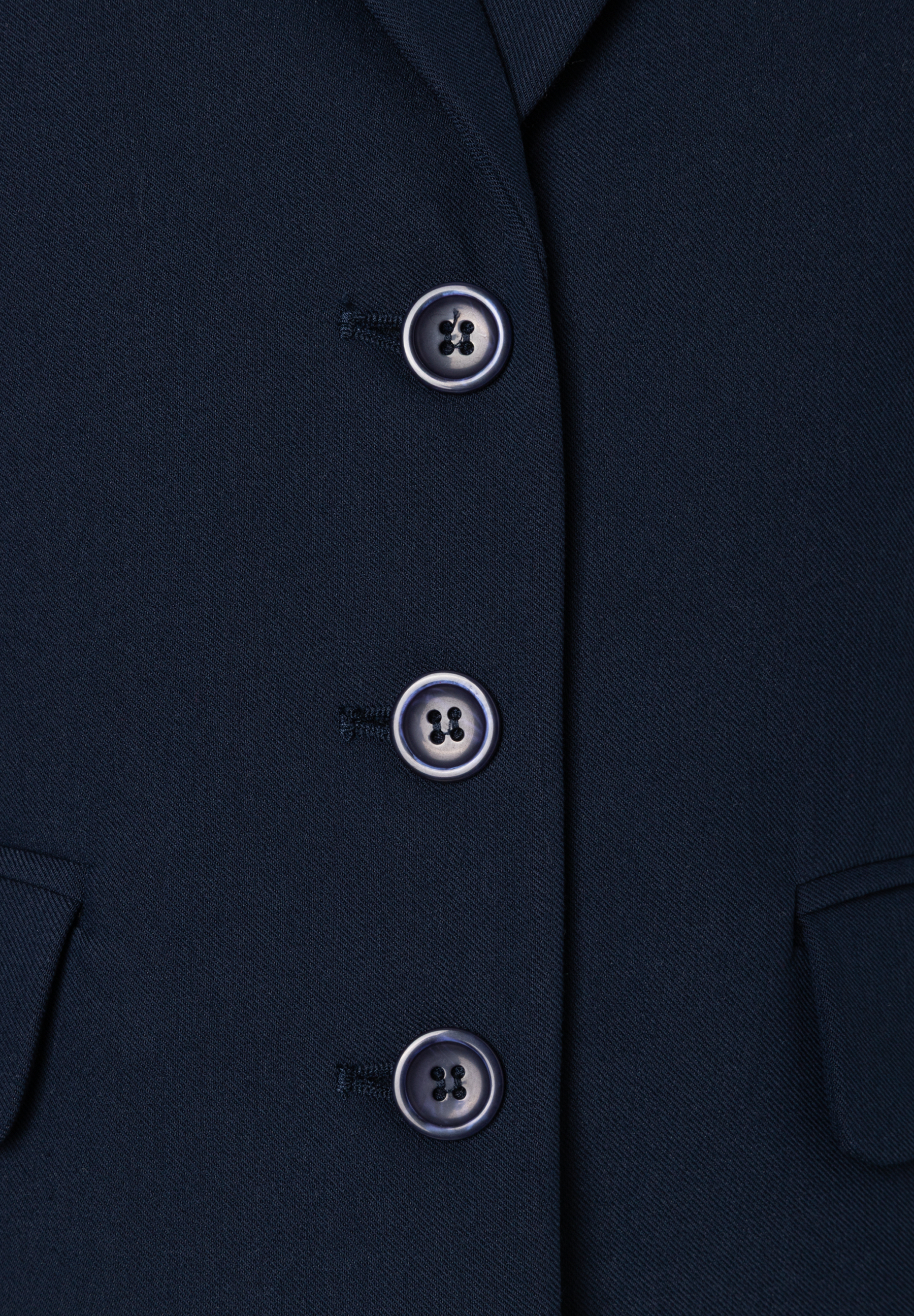 Nahaufnahme eines blauen MORE & MORE Blazers mit drei Knöpfen und Webware-Material. Nahaufnahme eines blauen MORE & MORE Blazers mit drei Knöpfen und Webware-Material.