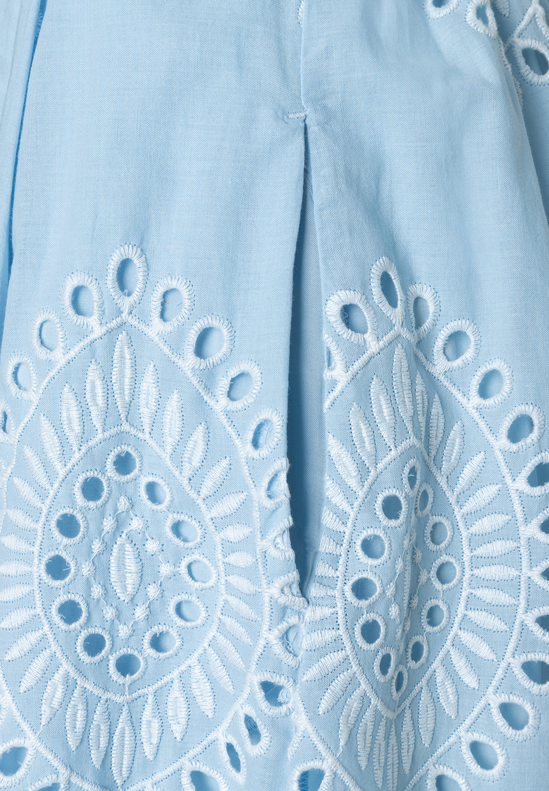 Nahaufnahme eines hellblauen MORE & MORE Rocks mit floraler Lochstickerei. Nahaufnahme eines hellblauen MORE & MORE Rocks mit floraler Lochstickerei.