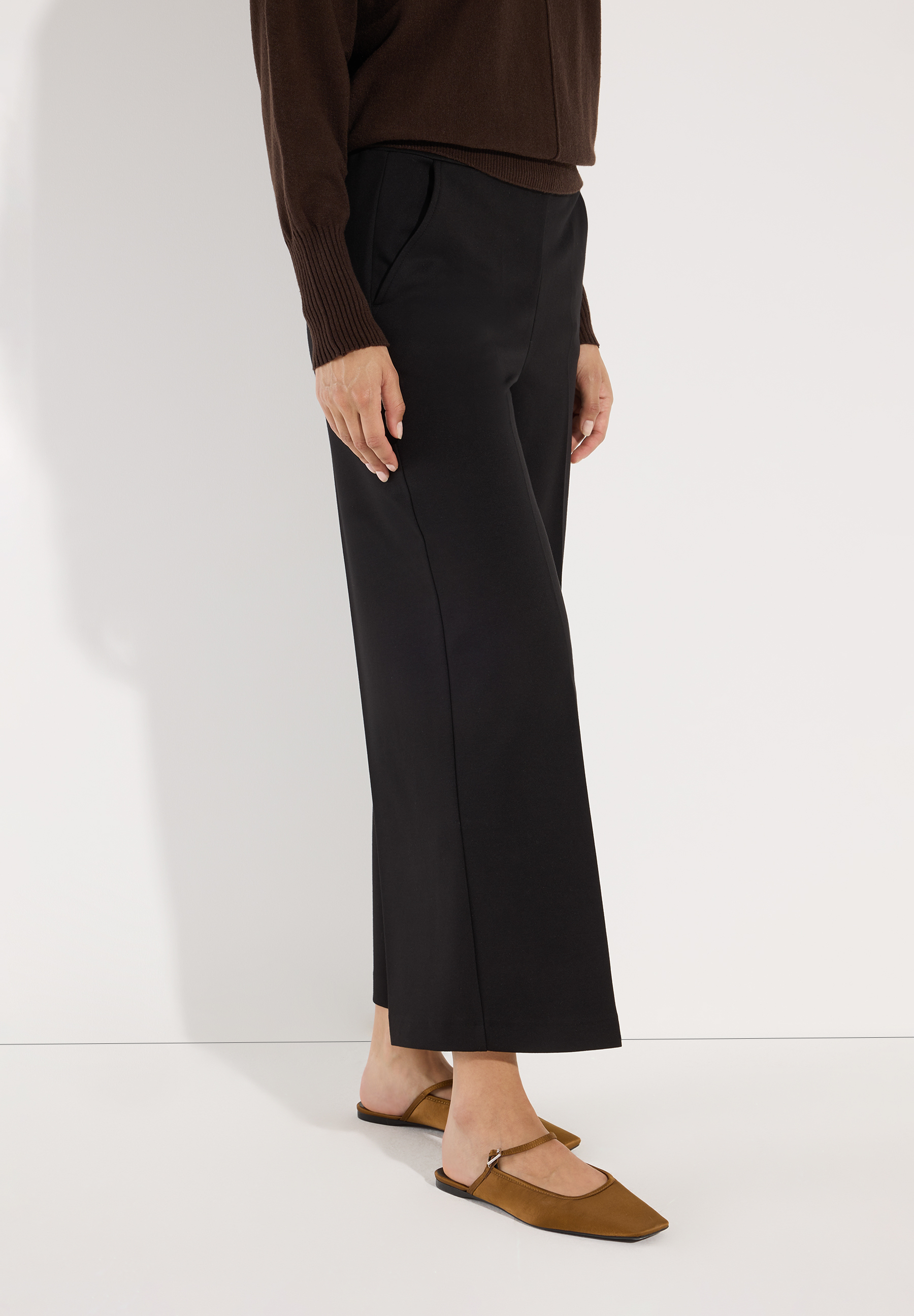 MORE & MORE schwarze Culottes kombiniert mit einem braunen Pullover & Slingbacks vor weißem Hintergrund.