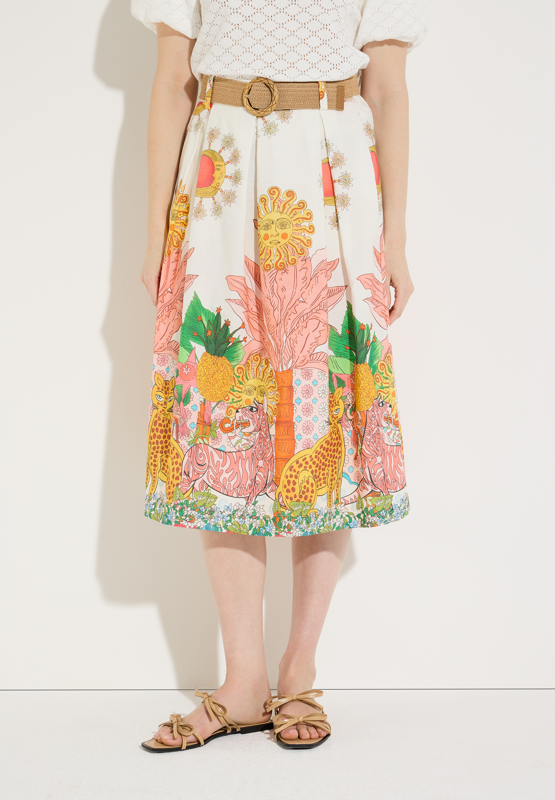 Ein Rock von MORE & MORE mit buntem Print, kombiniert mit einer weißen Bluse und braunen Sandalen.