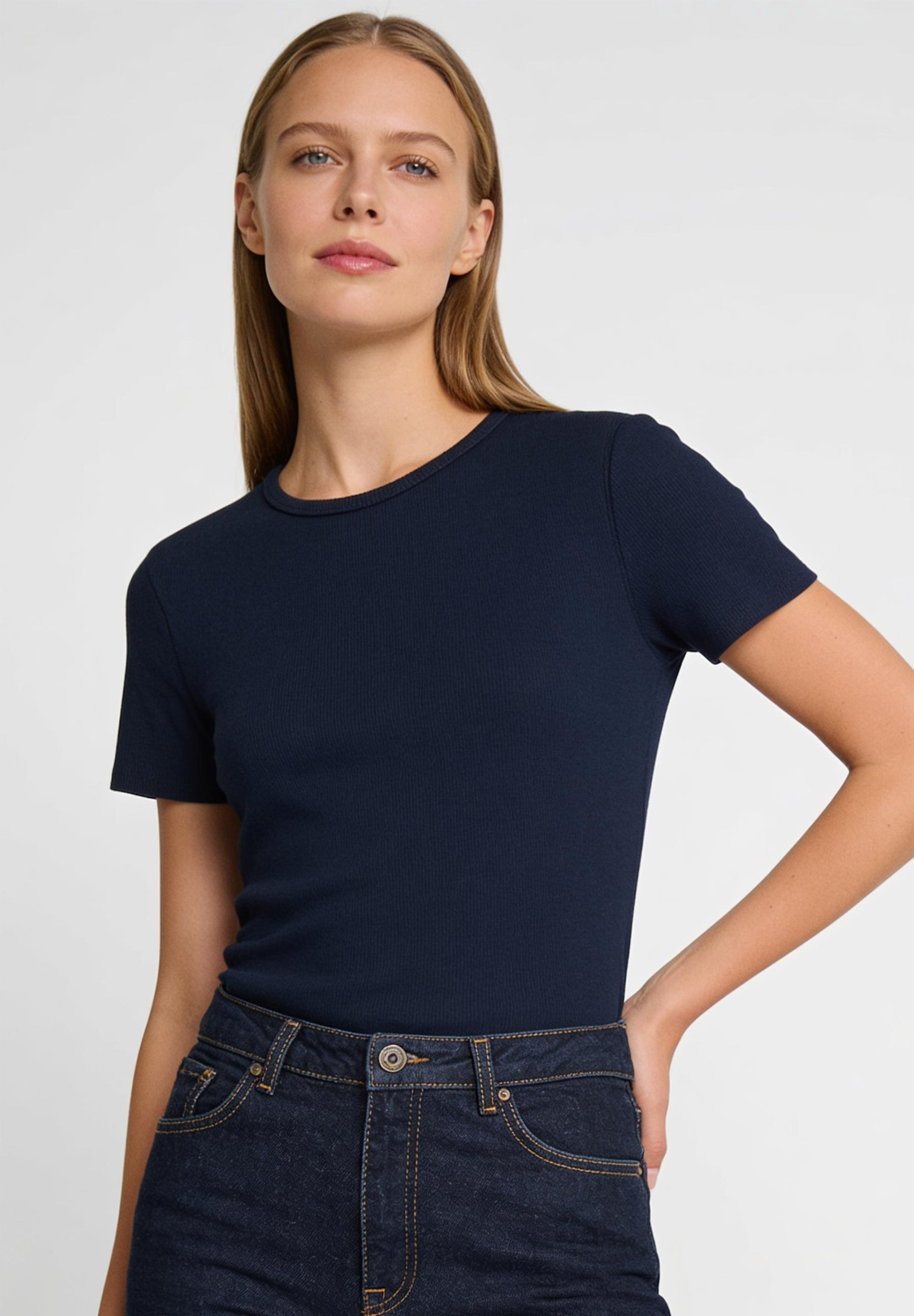 AI generated - MORE & MORE geripptes T-Shirt in Navy kombiniert mit Jeans, das Model steht mit der Hand in der Hüfte.