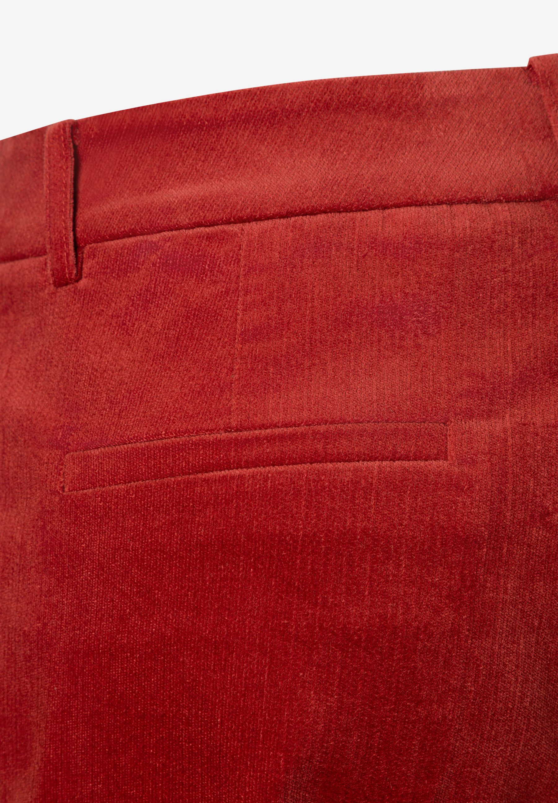 MORE & MORE Damenhose aus rotem Samt-Stretchmaterial, Nahaufnahme einer Gesäßtasche. MORE & MORE Damenhose aus rotem Samt-Stretchmaterial, Nahaufnahme einer Gesäßtasche.