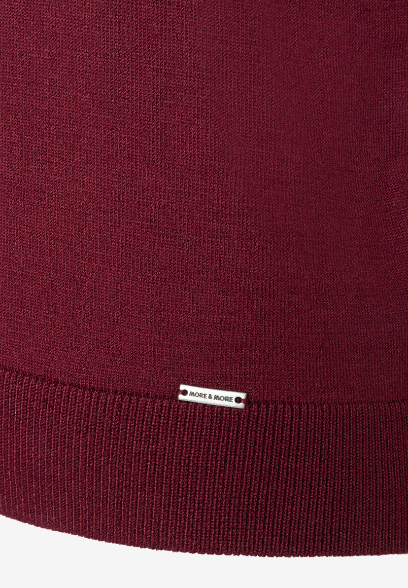 MORE & MORE Pullover aus weinrotem Rippstrick. Ein silbernes Logo-Etikett ist auf dem unteren Saum aufgenäht.
