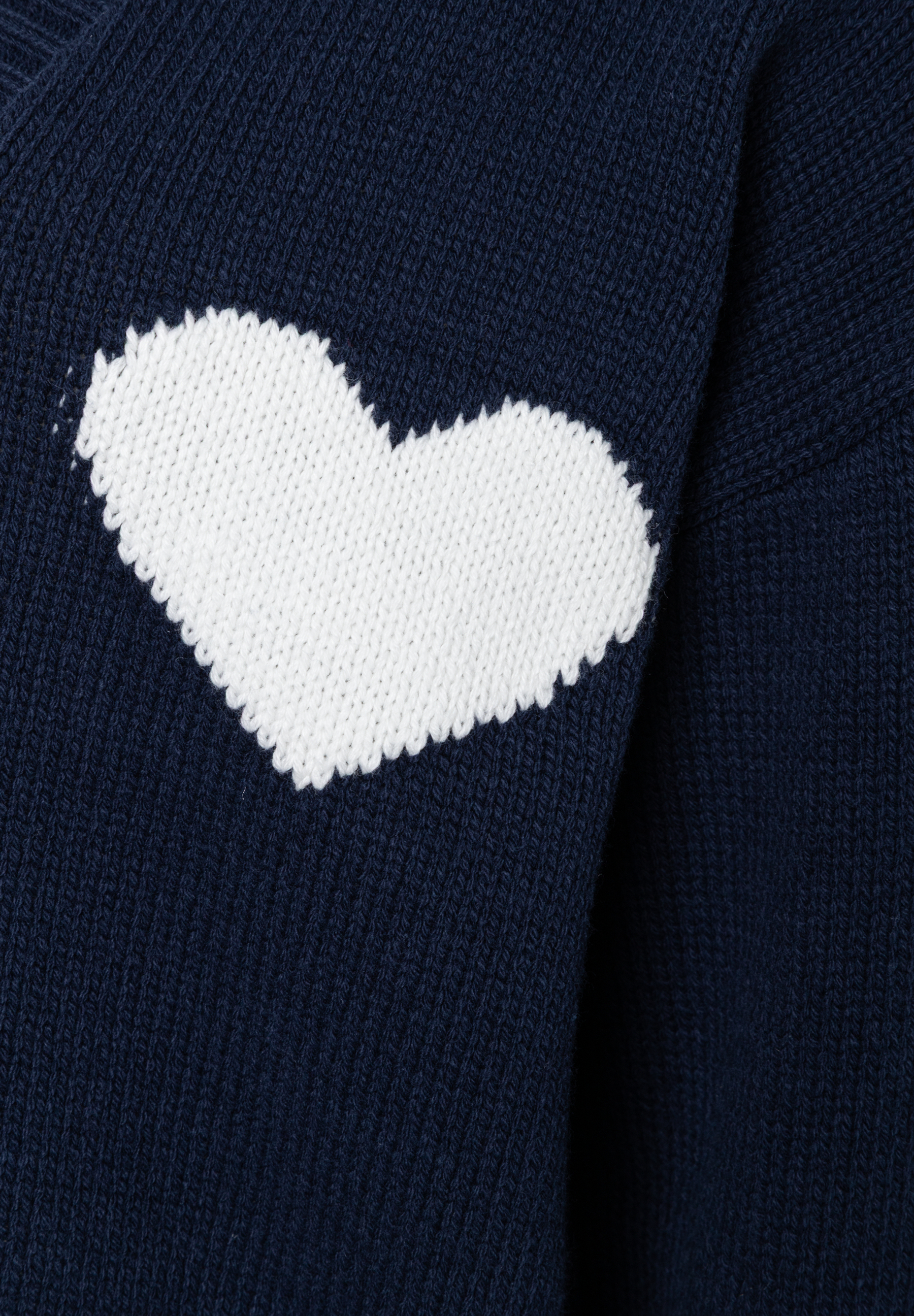 Detailansicht eines dunkelblauen MORE & MORE Strickoberteils mit weißem Herzmuster. Detailansicht eines dunkelblauen MORE & MORE Strickoberteils mit weißem Herzmuster.