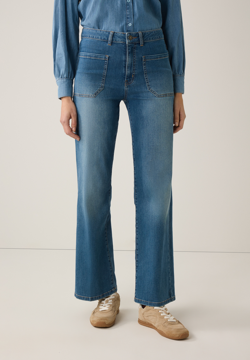 Eine Person in MORE & MORE Jeans mit aufgesetzten Taschen, kombiniert mit einem Denim-Oberteil und hellbraunen Sneakers. Eine Person in MORE & MORE Jeans mit aufgesetzten Taschen, kombiniert mit einem Denim-Oberteil und hellbraunen Sneakers.