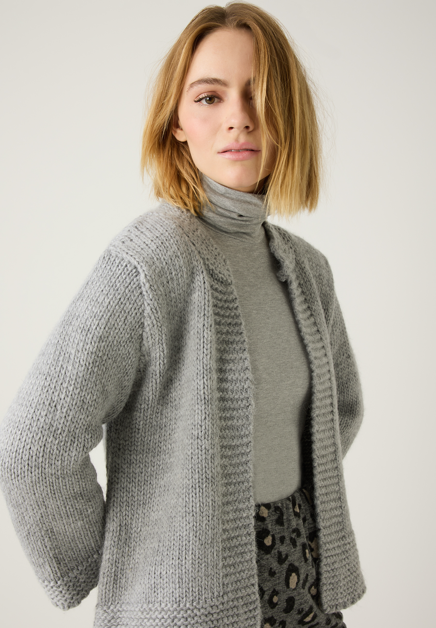 Eine Frau mit MORE & MORE Strick-Oberteil in Grau, das für Wärme und angenehmen Tragekomfort sorgt.