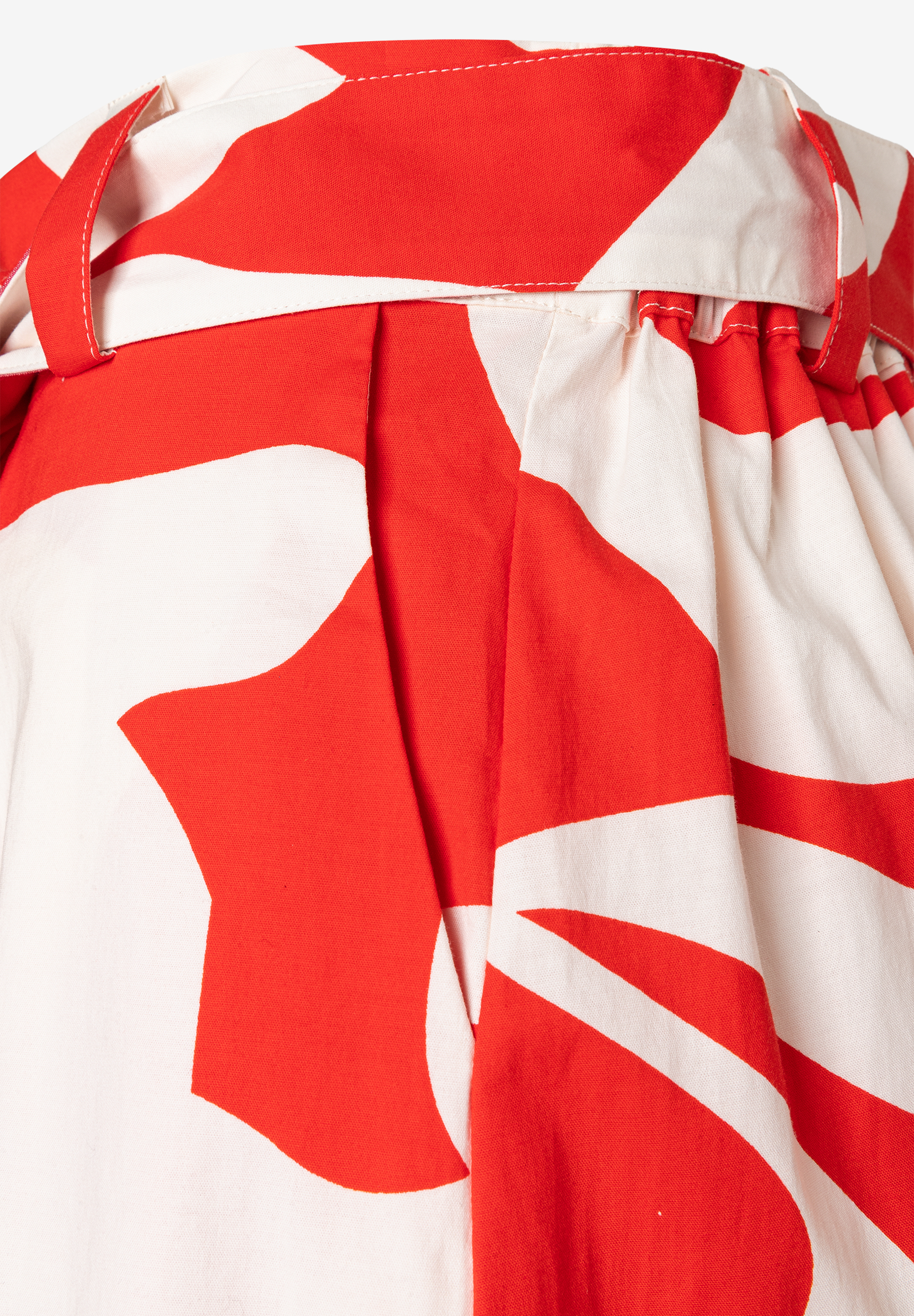 Nahaufnahme eines MORE & MORE Rocks mit auffälligem, rot-weißem Muster und einem Stoffgürtel. Nahaufnahme eines MORE & MORE Rocks mit auffälligem, rot-weißem Muster und einem Stoffgürtel.