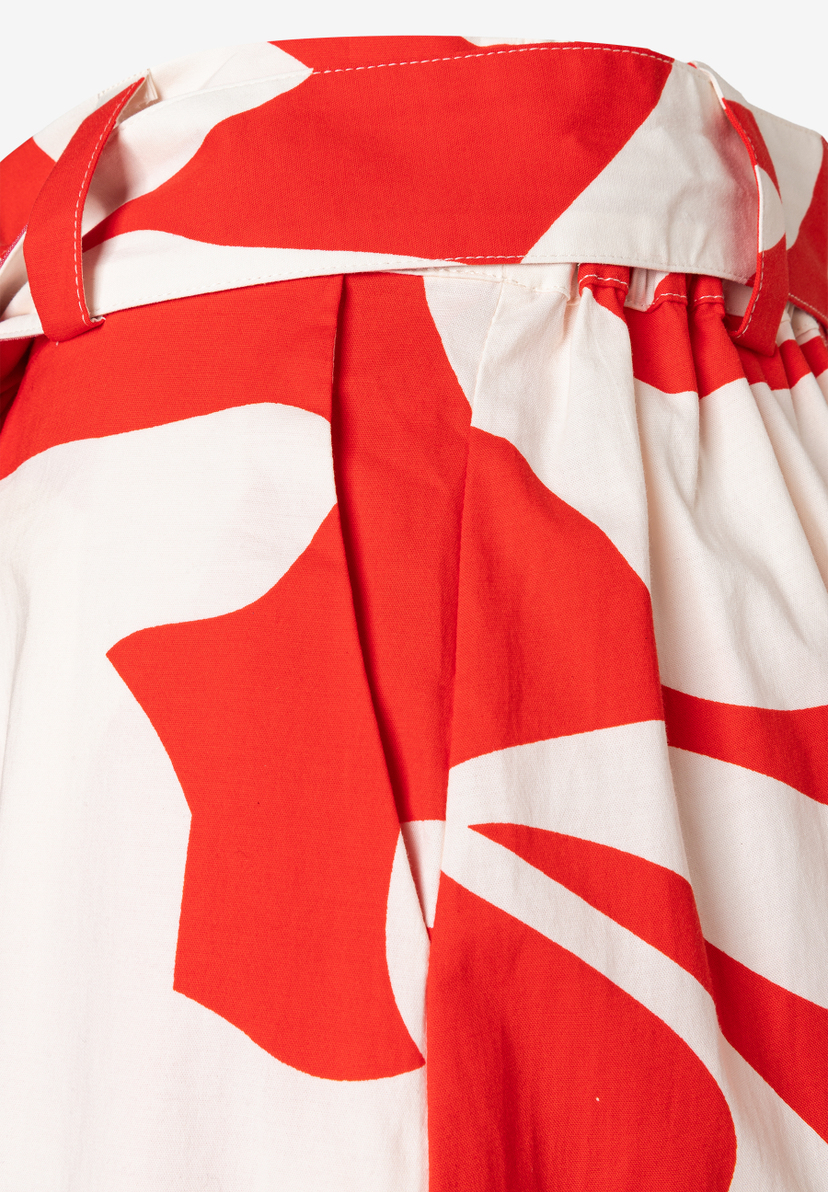 Nahaufnahme eines MORE & MORE Rocks mit auffälligem, rot-weißem Muster und einem Stoffgürtel. Nahaufnahme eines MORE & MORE Rocks mit auffälligem, rot-weißem Muster und einem Stoffgürtel.