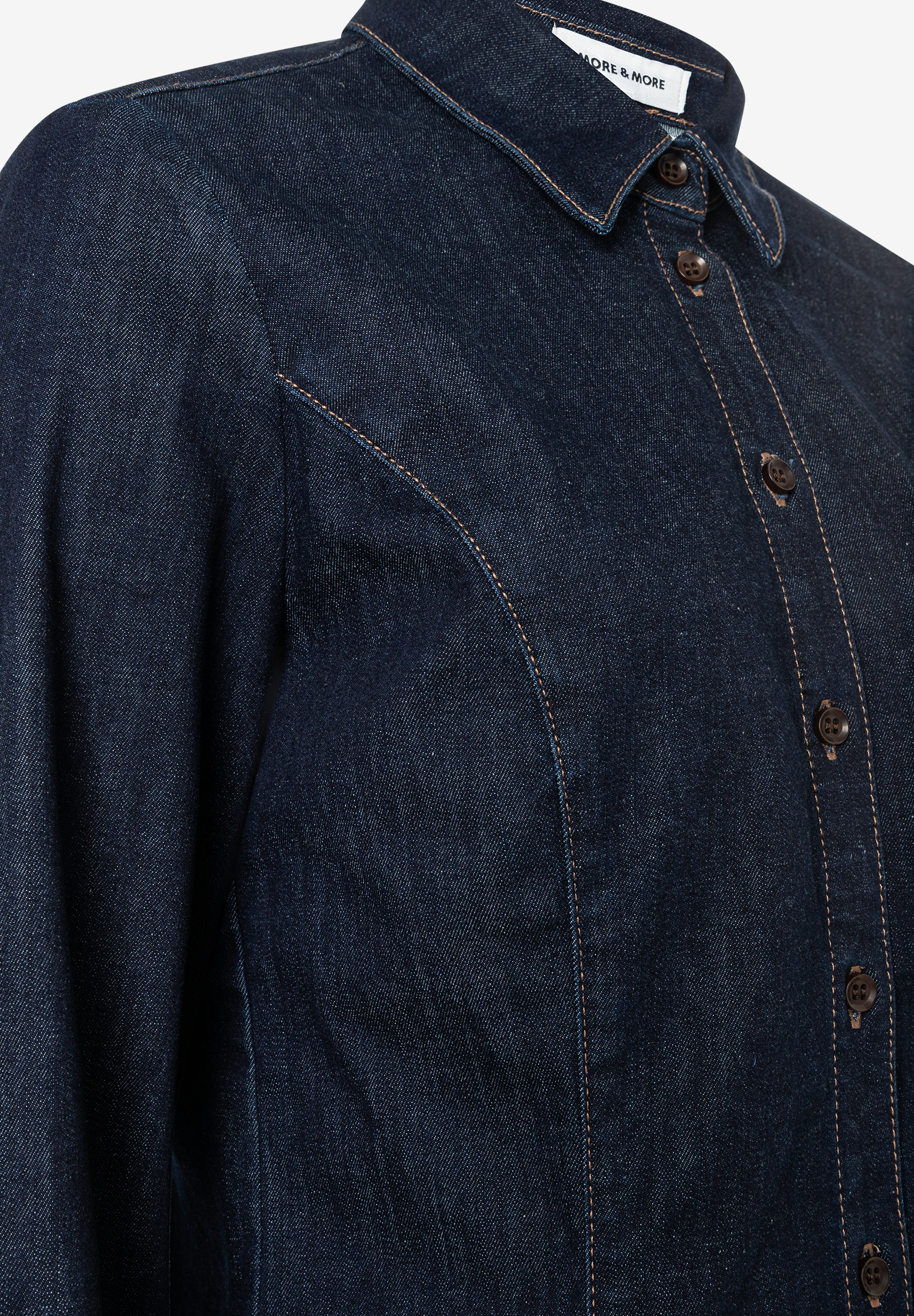 Nahaufnahme einer dunkelblauen MORE & MORE Jeansbluse mit braunen Knöpfen. Nahaufnahme einer dunkelblauen MORE & MORE Jeansbluse mit braunen Knöpfen.