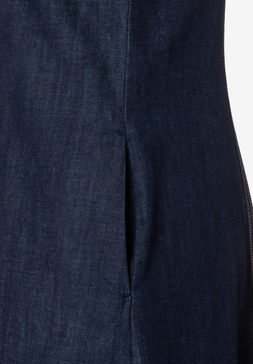 Nahaufnahme eines MORE & MORE Oberteils aus blauem Denim mit Schlitz. Nahaufnahme eines MORE & MORE Oberteils aus blauem Denim mit Schlitz.