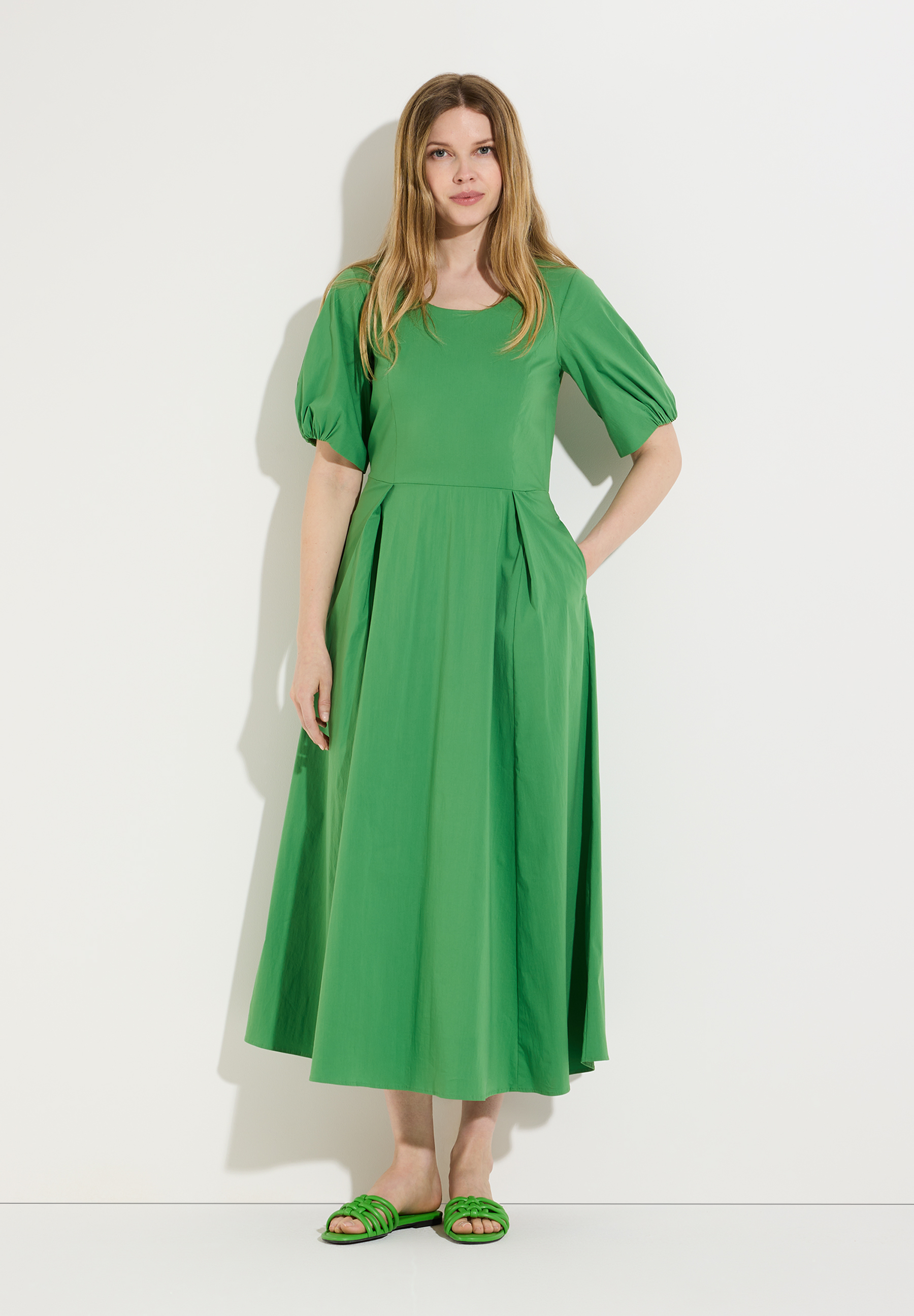 Eine schlanke, blonde Frau im MORE & MORE Kleid aus Popeline, das angenehm und hautfreundlich ist. Dazu trägt sie grüne Sandalen. Eine schlanke, blonde Frau im MORE & MORE Kleid aus Popeline, das angenehm und hautfreundlich ist. Dazu trägt sie grüne Sandalen.