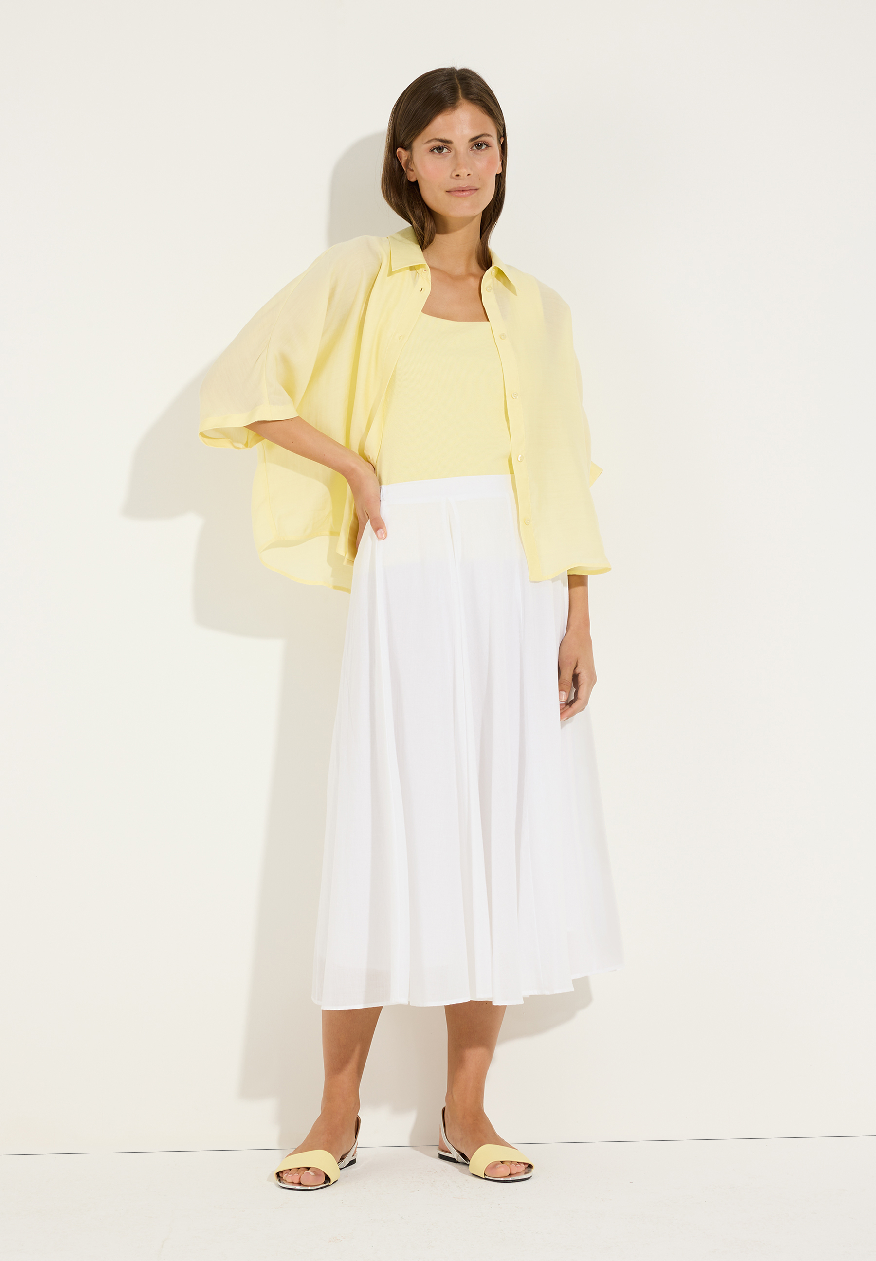 MORE & MORE Bluse: Eine junge Frau posiert in einer gelben Bluse (Webware) und passendem Top mit einem weißen Rock. MORE & MORE Bluse: Eine junge Frau posiert in einer gelben Bluse (Webware) und passendem Top mit einem weißen Rock.
