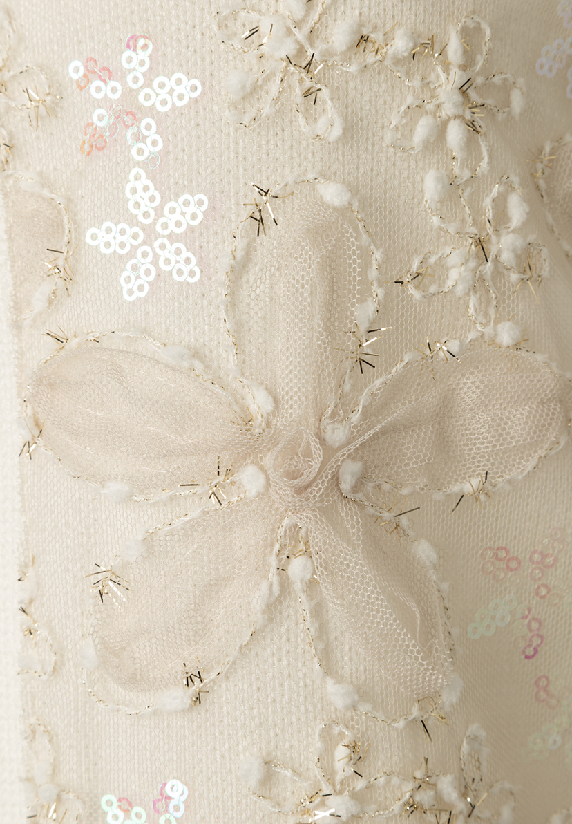 Detailansicht eines MORE & MORE Strick-Oberteils mit Blumenmuster und Pailletten. Detailansicht eines MORE & MORE Strick-Oberteils mit Blumenmuster und Pailletten.
