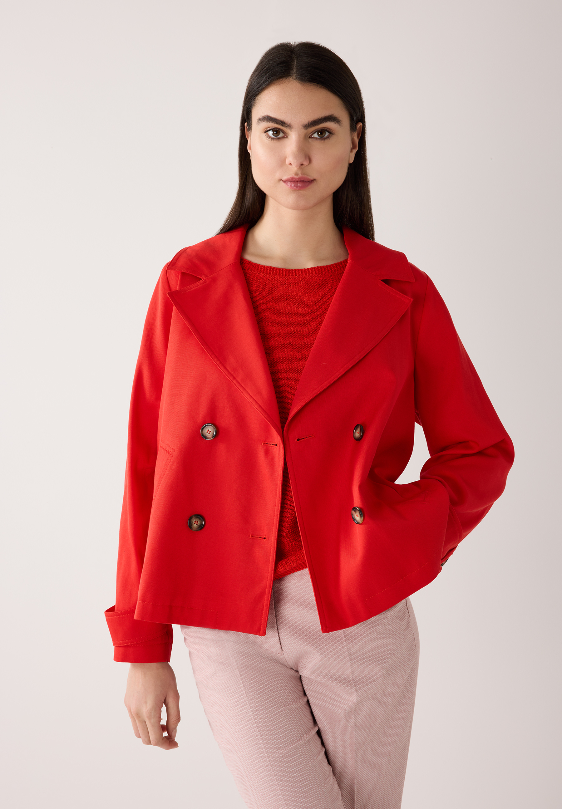 Eine Frau mit einem roten MORE & MORE Oberteil, kombiniert mit einer passenden Hose.