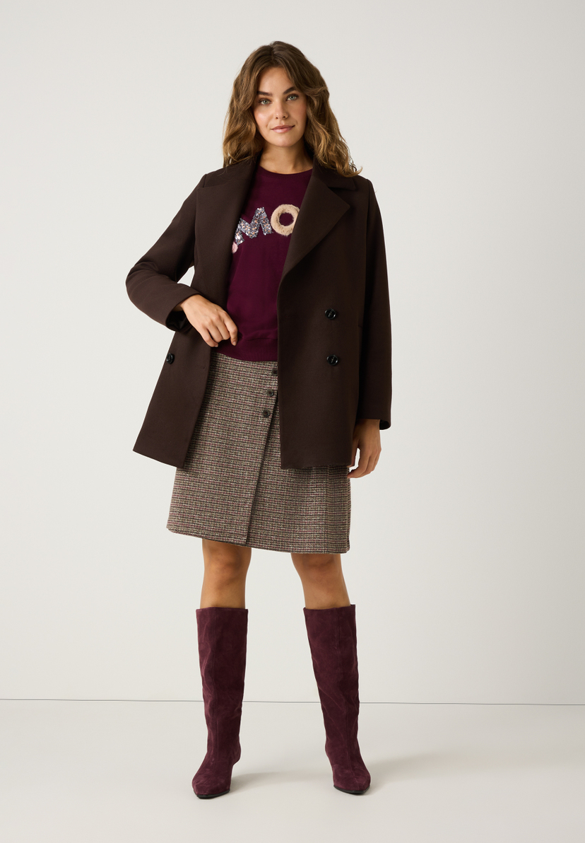 Eine Frau in MORE & MORE Oberteilen: braunem Kurzmantel, bordeauxrotem Shirt und Rock. Dazu farblich passende Stiefel. Eine Frau in MORE & MORE Oberteilen: braunem Kurzmantel, bordeauxrotem Shirt und Rock. Dazu farblich passende Stiefel.