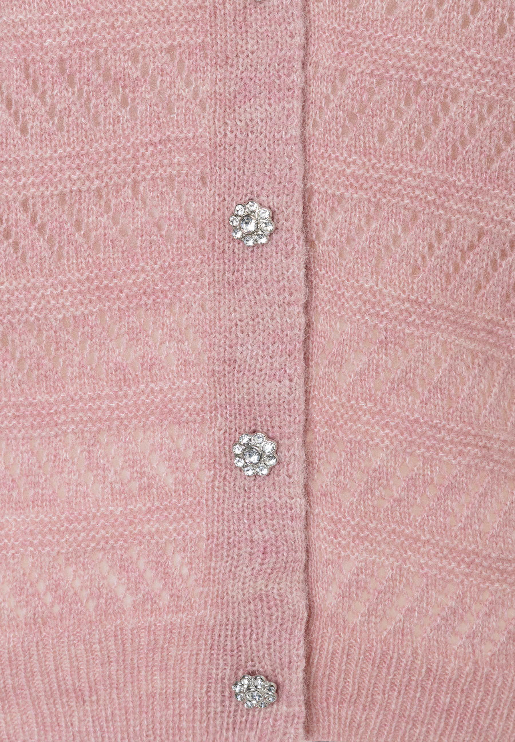 Nahaufnahme eines rosa MORE & MORE Oberteils mit Lochstrick und glitzernden Zierknöpfen. Nahaufnahme eines rosa MORE & MORE Oberteils mit Lochstrick und glitzernden Zierknöpfen.