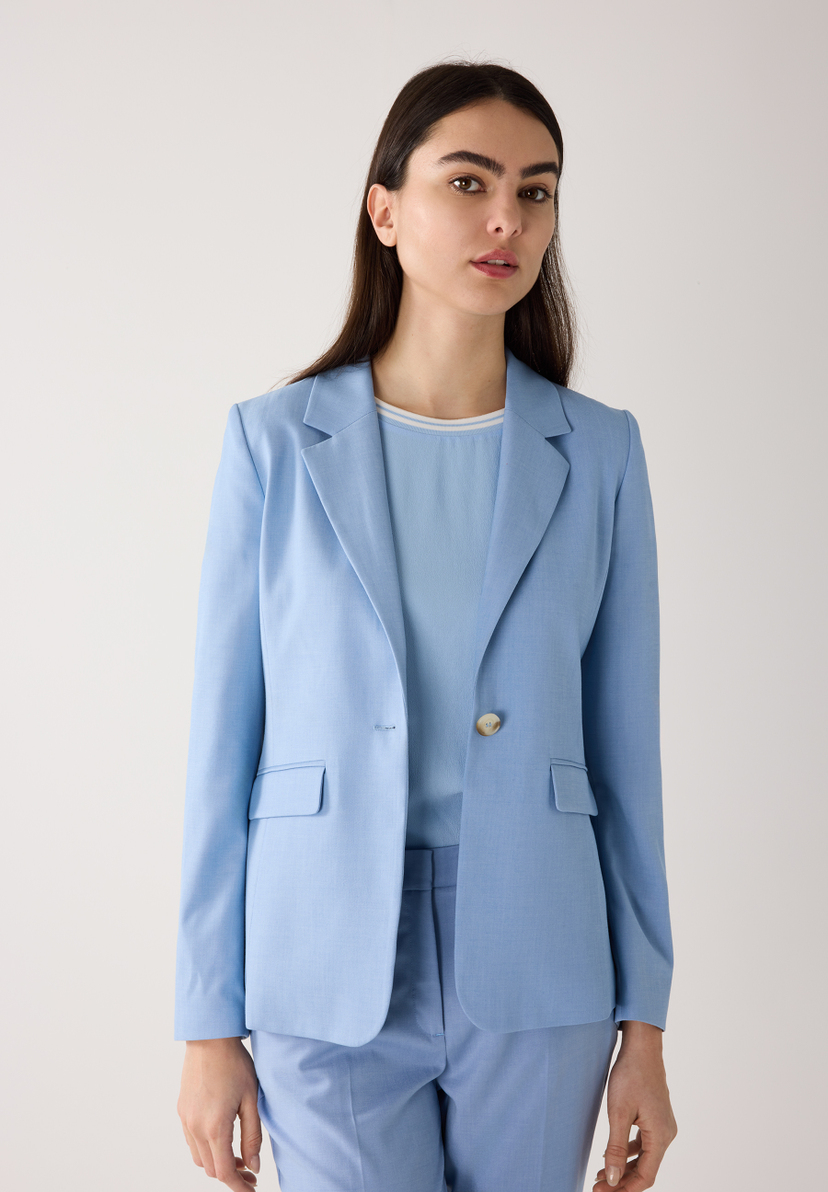 Eine Frau im hellblauen MORE & MORE Blazer mit Webware und Stretch-Materialkonstruktion, posiert vor einem hellen Hintergrund. Eine Frau im hellblauen MORE & MORE Blazer mit Webware und Stretch-Materialkonstruktion, posiert vor einem hellen Hintergrund.