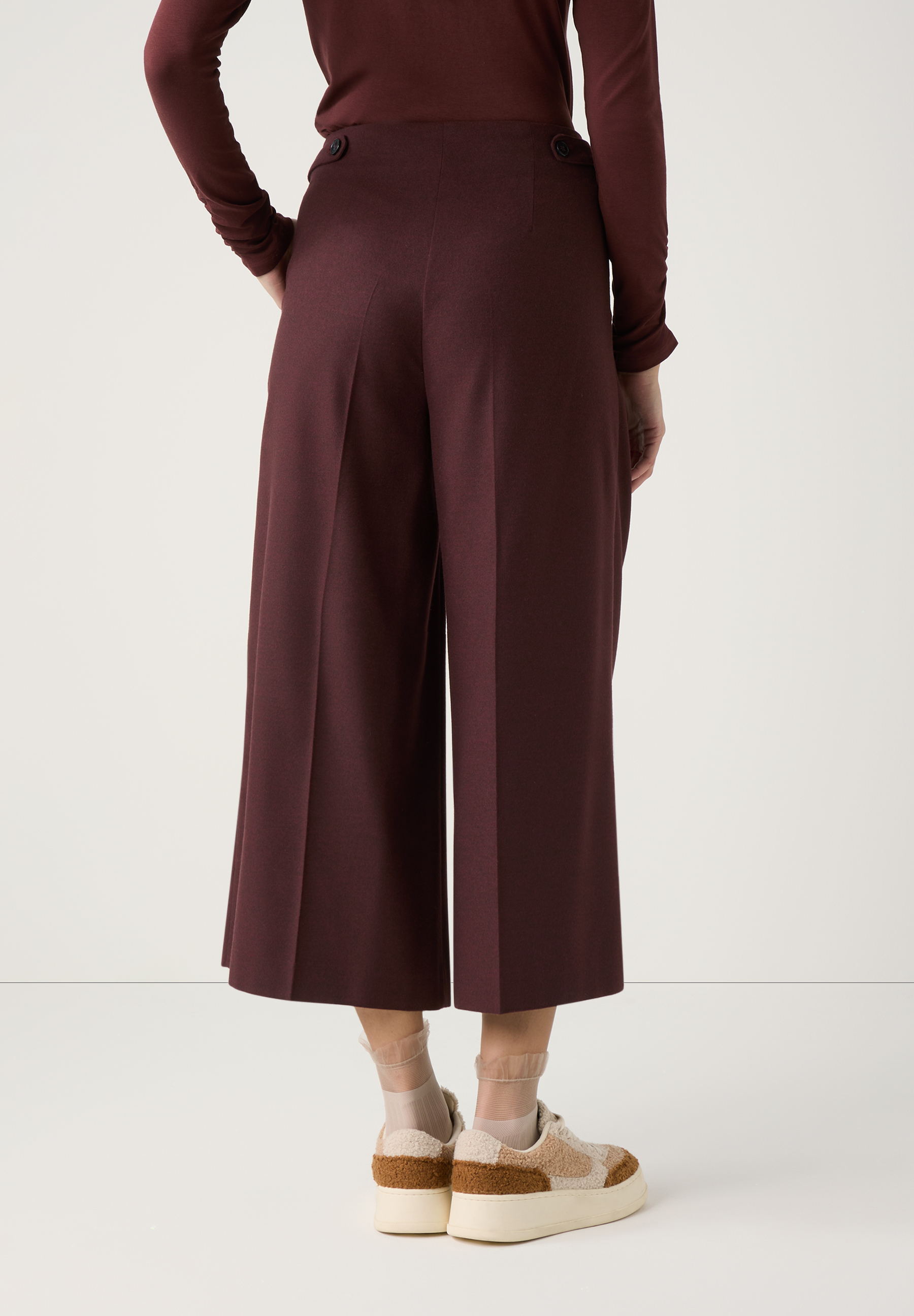 Eine Person trägt MORE & MORE Hosen in Pflaumenfarbe, dazu ein langärmliges Oberteil und Sneaker. Eine Person trägt MORE & MORE Hosen in Pflaumenfarbe, dazu ein langärmliges Oberteil und Sneaker.