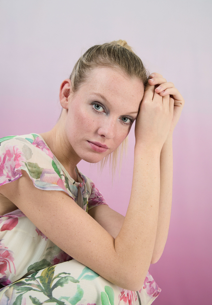 Eine Frau mit einem Chiffon-Oberteil von MORE & MORE posiert vor einem rosa Hintergrund. Eine Frau mit einem Chiffon-Oberteil von MORE & MORE posiert vor einem rosa Hintergrund.